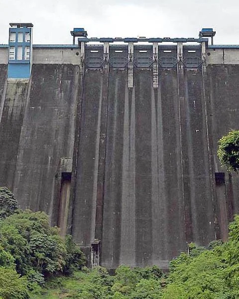 Large concrete dam with spillways and greenery at the base.