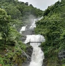 A multi-tiered waterfall flowing down a lush green hillside.