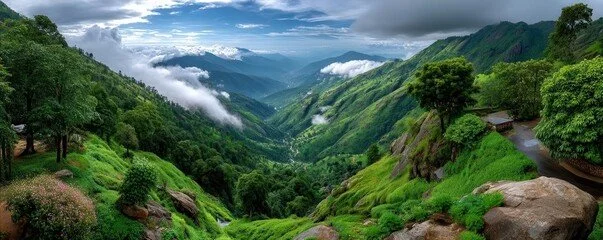 Lush green mountains with a winding road and clouds in the valley.