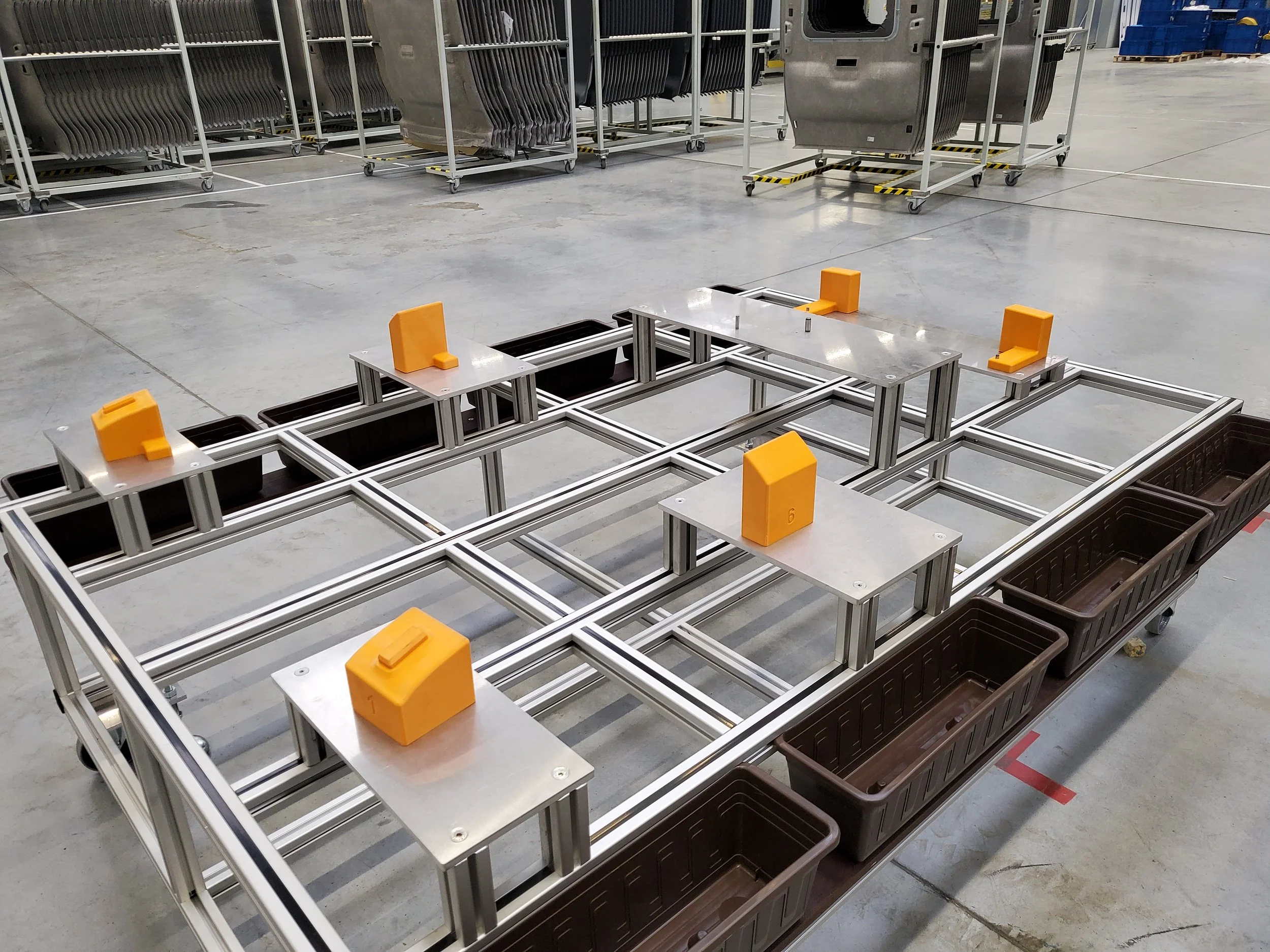Mobilní montážní stanoviště s oranžovými 3D tištěnými zakládacími prvky ve výrobním prostředí.