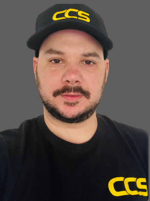 A man wearing a black cap with yellow lettering and a black T-shirt with yellow logo against a gray background.