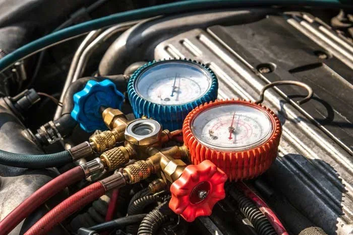 Automobile engine with manifold gauges connected to the air conditioning system.