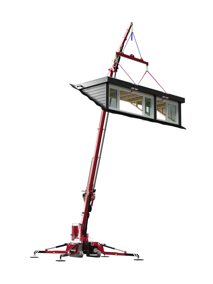 A red construction crane lifting a small modular building with large windows into the air.