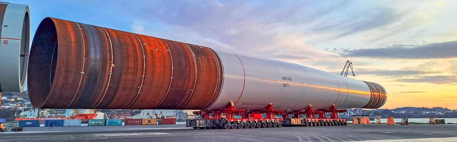 A large rocket stage on a transport platform at sunset.