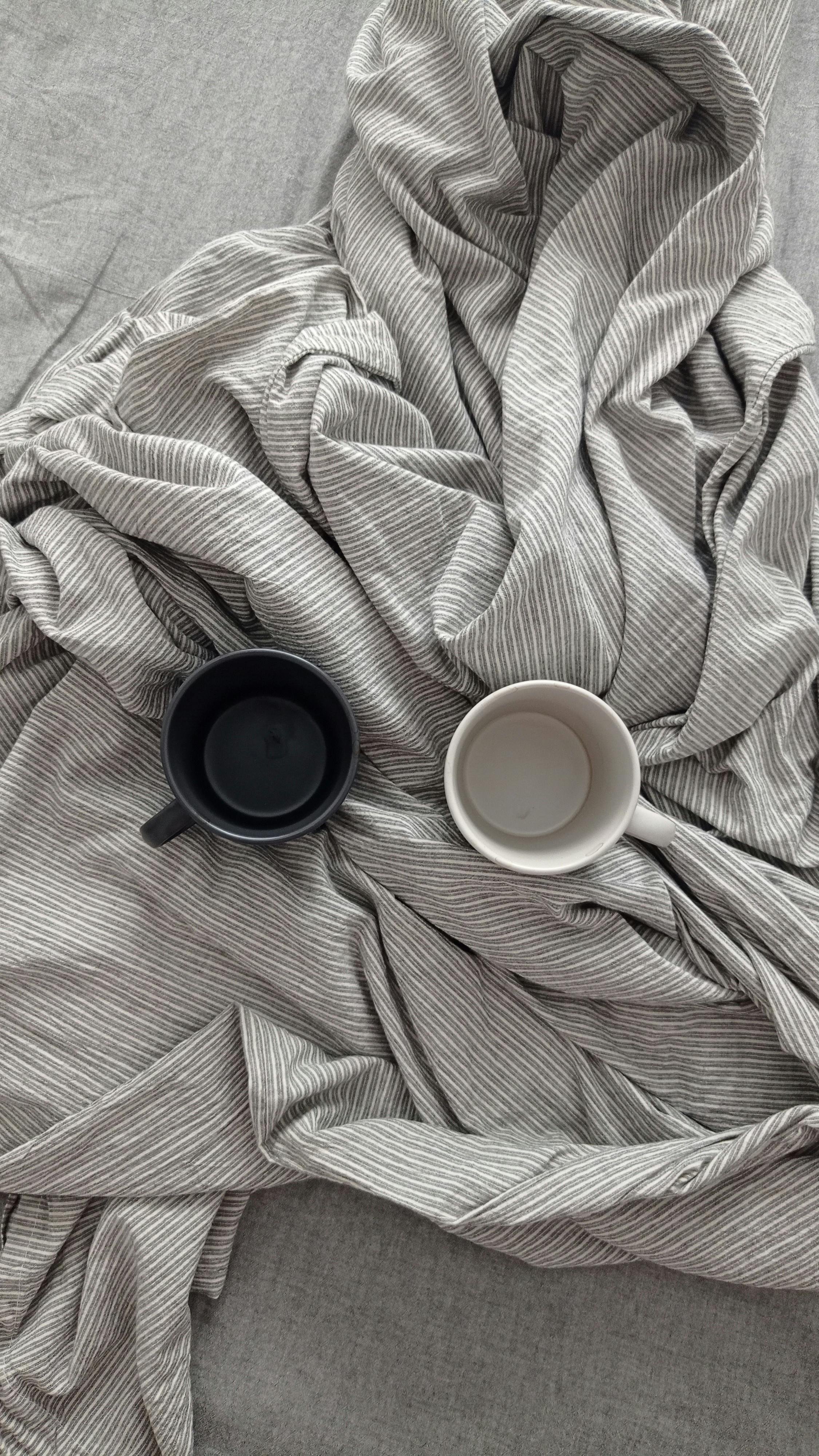 Two coffee mugs, one black and one white on bedspread representing supportive therapy for parents and families