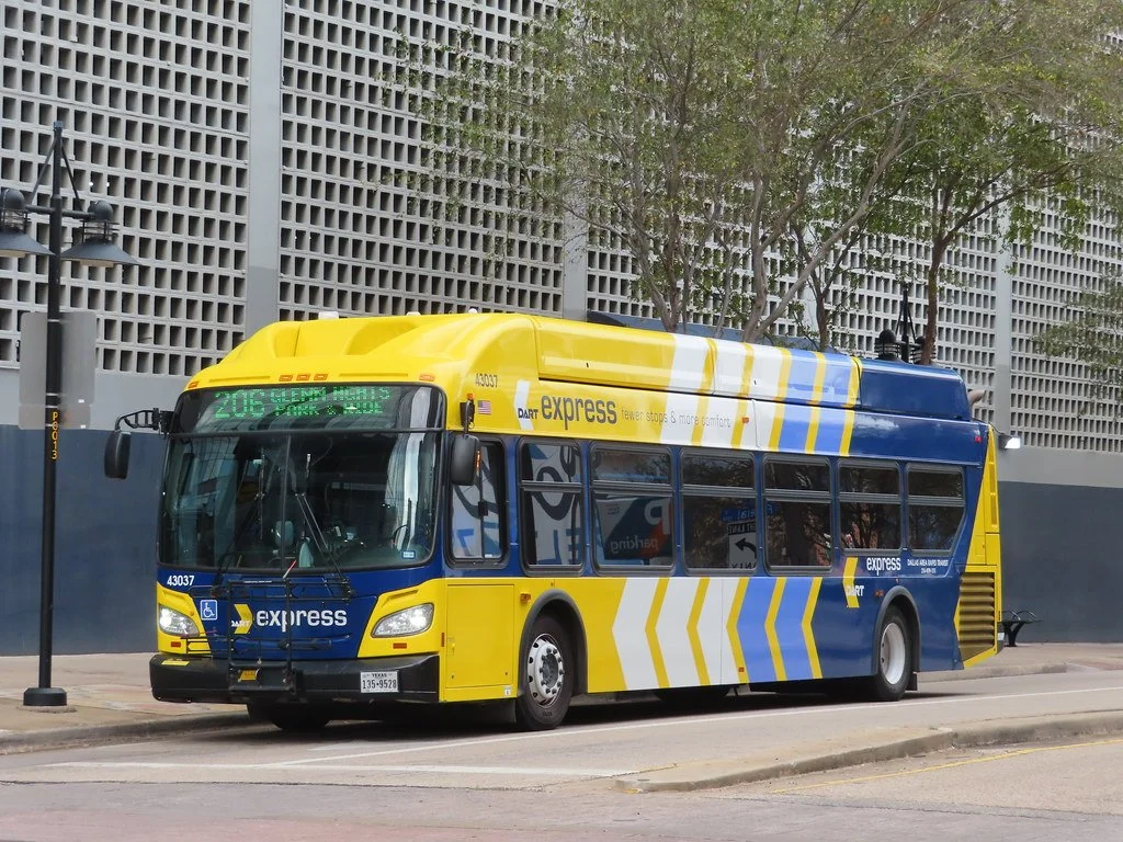A MARTA bus parked on the street in front of a modern building with trees.