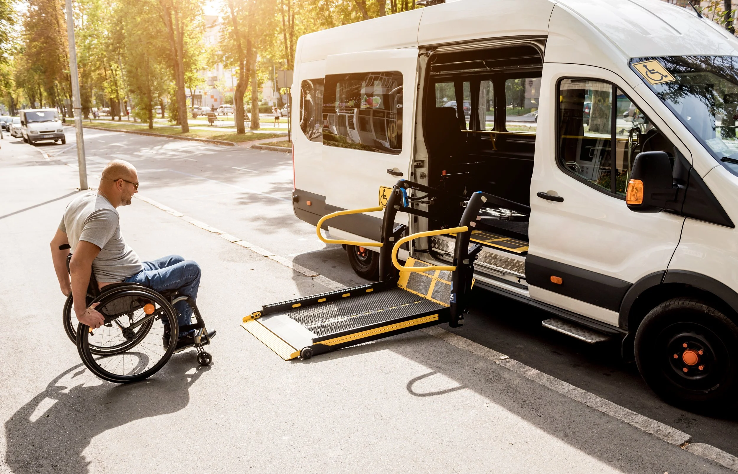A man in a wheelchair rolling onto a platform for an on-demand bus.