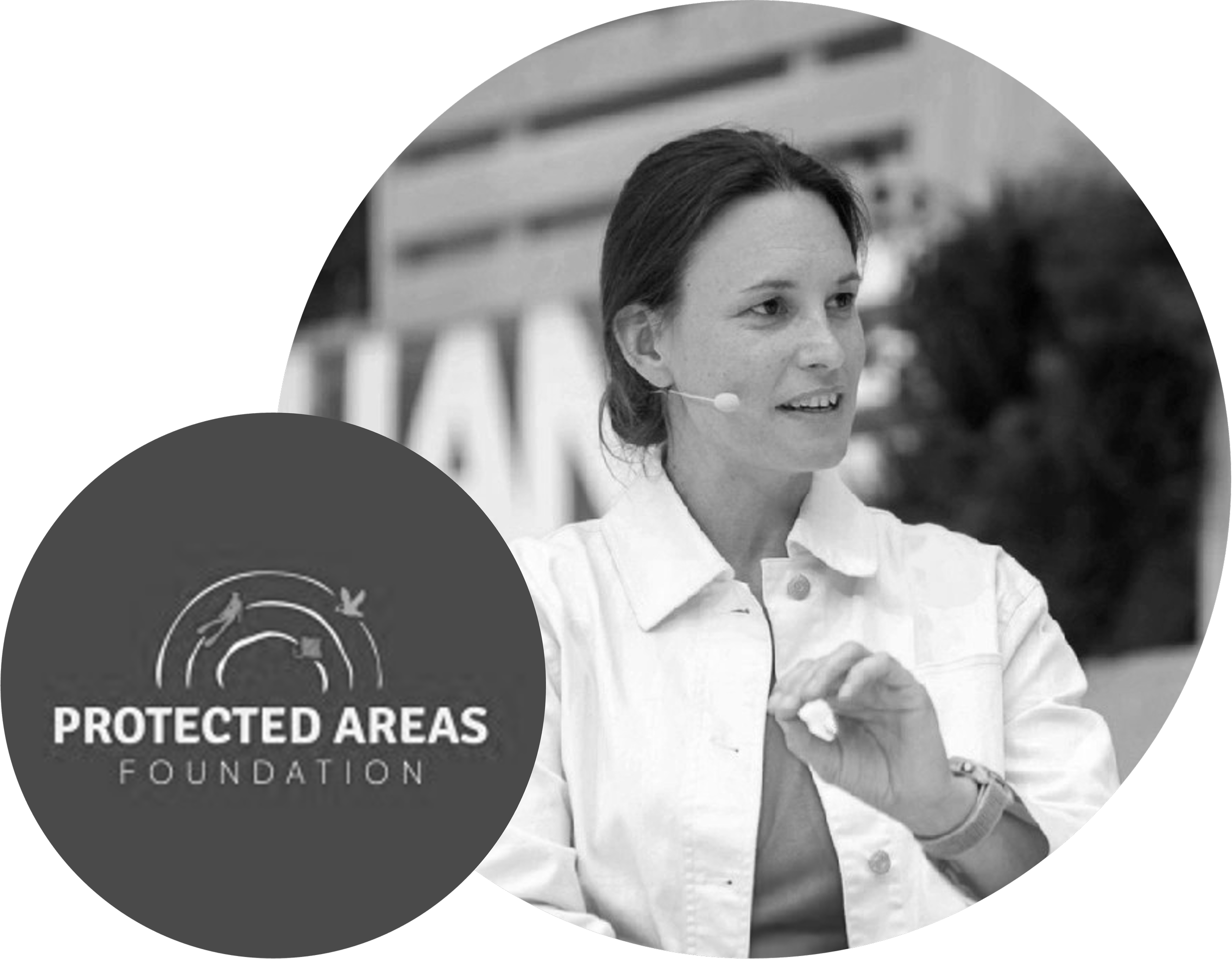 A woman speaking at an outdoor event with a microphone headset, gesturing with her hand, with the logo of Protected Areas Foundation in the foreground.