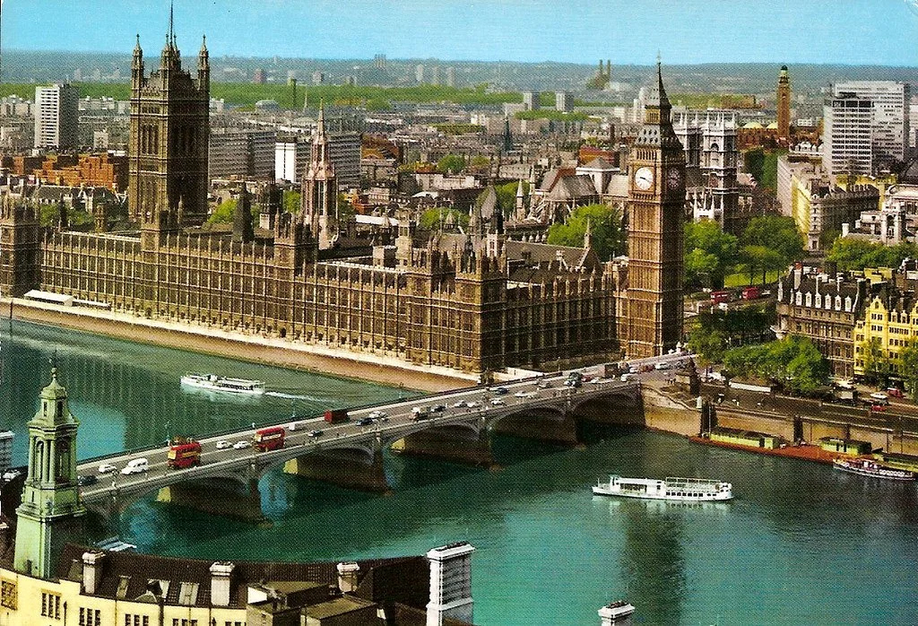 Aerial view of London showing the Houses of Parliament, Big Ben, Westminster Bridge, and the River Thames with boats sailing.