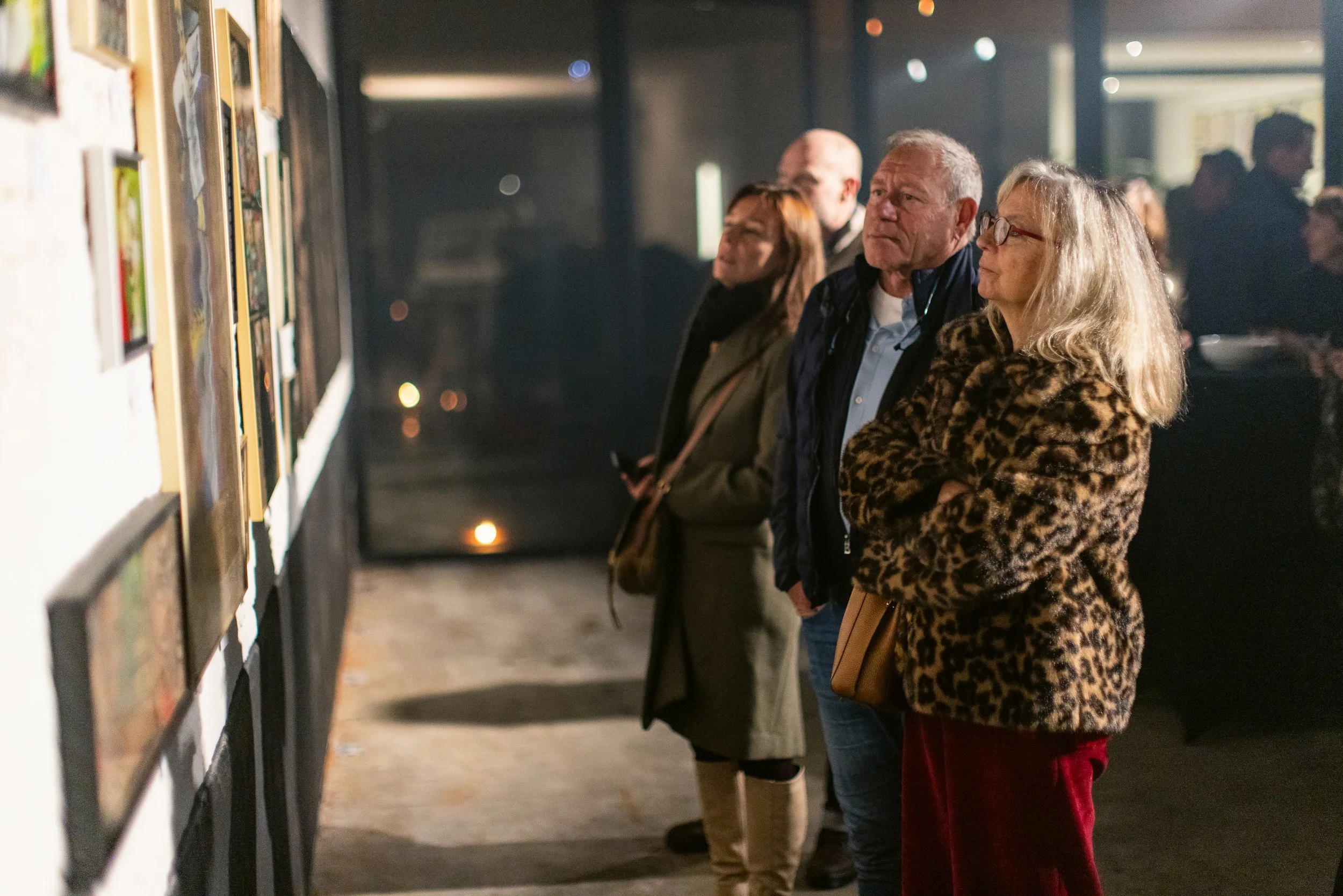 People viewing artwork at an art gallery in the evening.