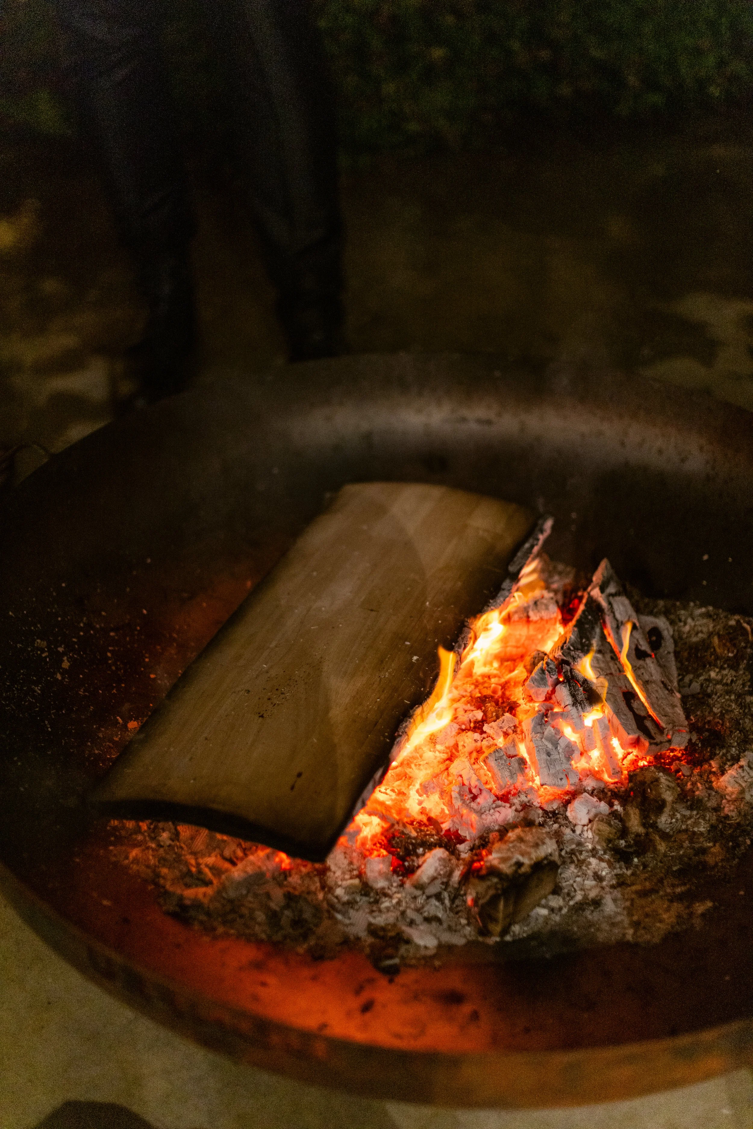 Campfire with burning logs in a fire pit at night
