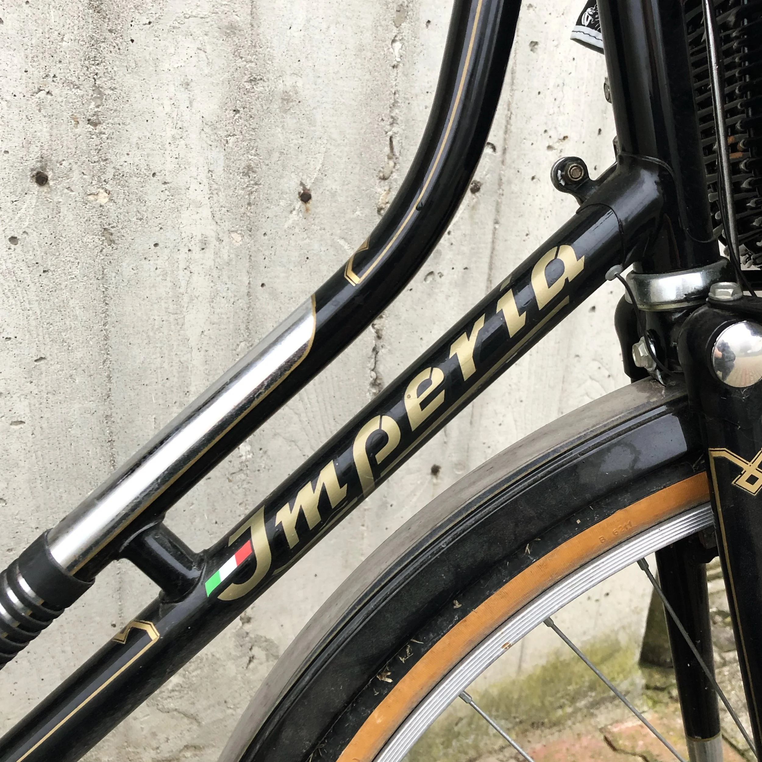 Foto di una bicicletta con telaio nero, scritta 'IMPERIA' in oro, con una piccola bandierina italiana sulla parte inferiore del telaio.