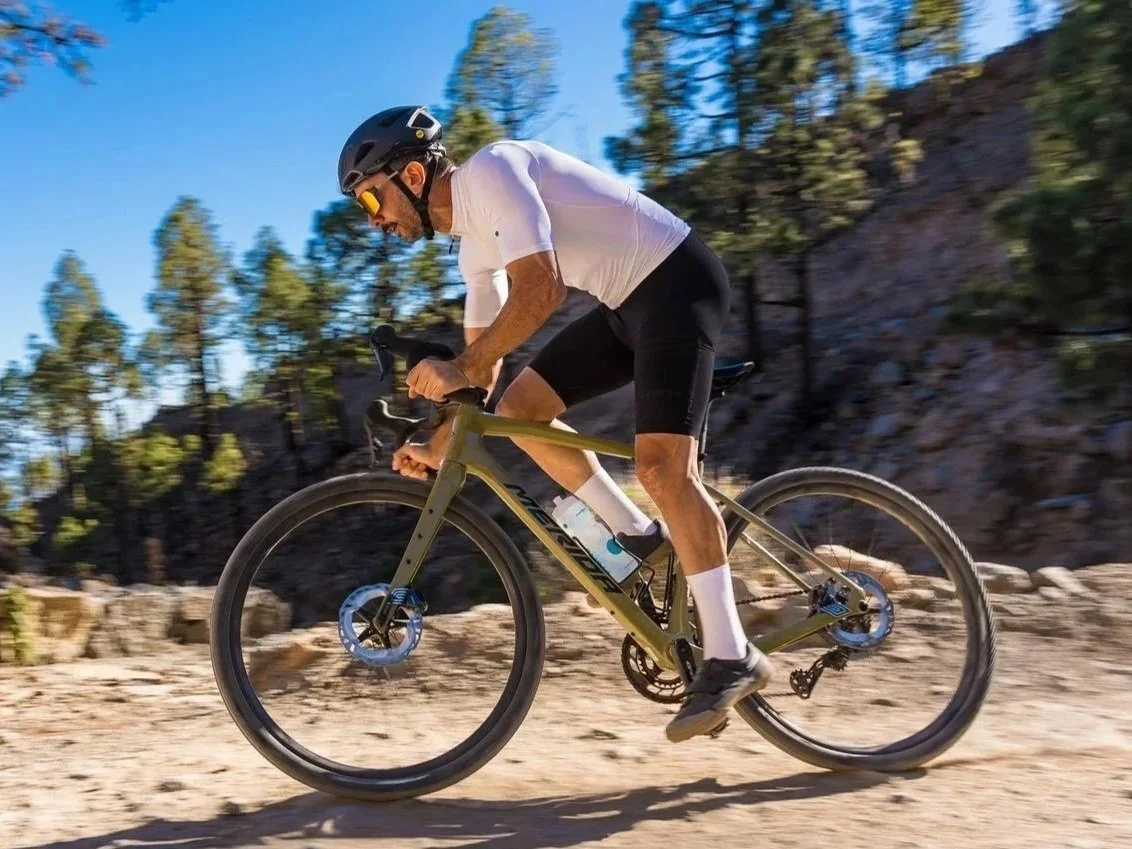 Uomo che pedala su una bicicletta da mountain bike in un paesaggio naturale con rocce e alberi sotto un cielo blu