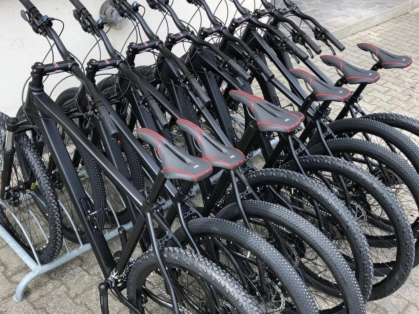 Raggruppamento di biciclette nere su un supporto in strada.
