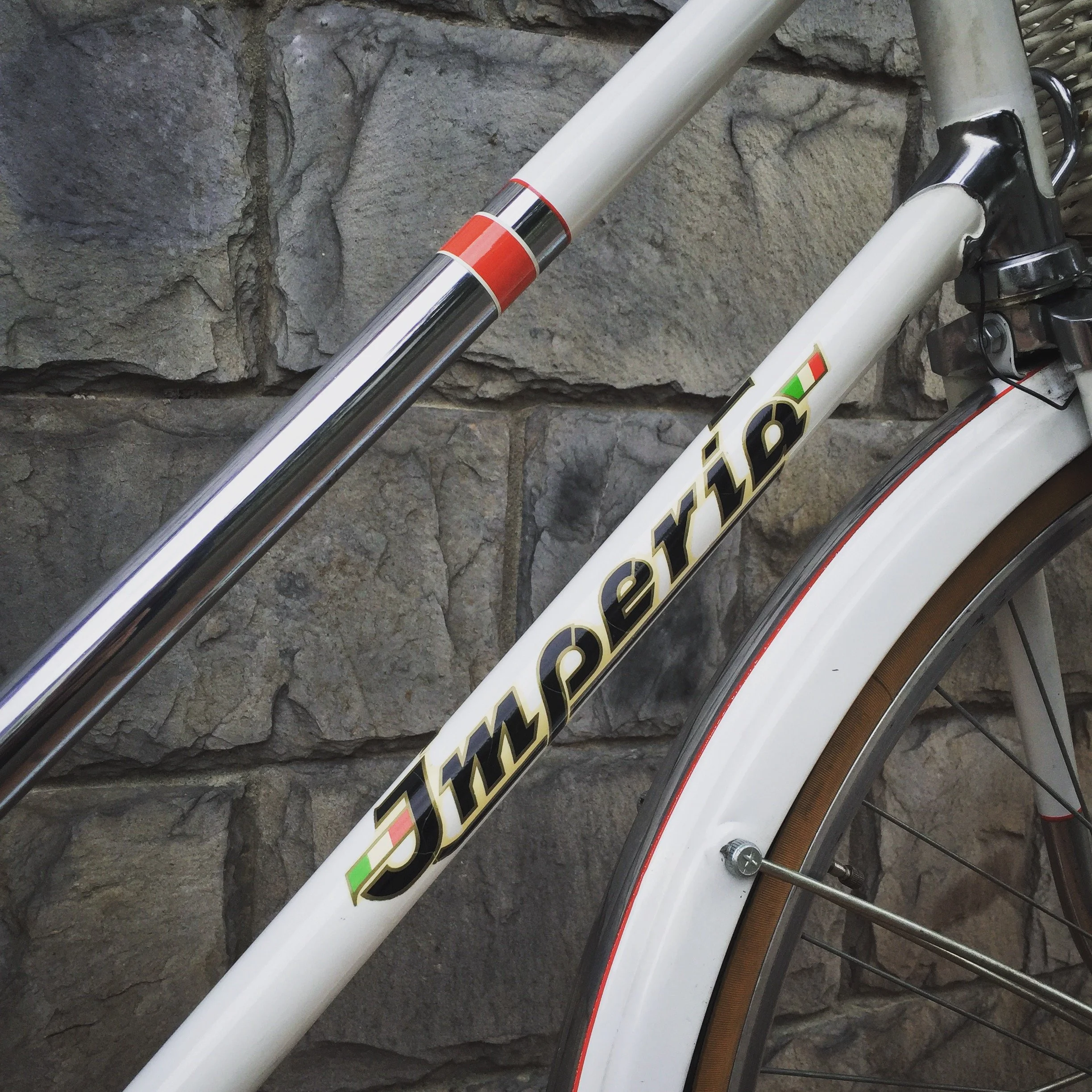 Particolare di una bicicletta con marchio Specialized, con telaio bianco, davanti a una parete in pietra.