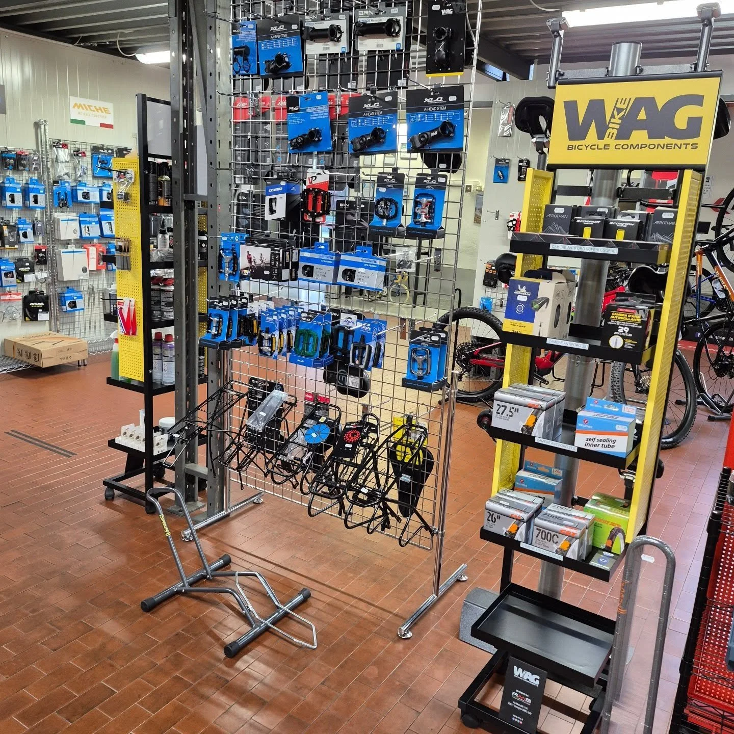 Esposizione di accessori per biciclette come luci, campanelli e altri componenti, con biciclette in secondo piano, in un negozio di articoli sportivi. Bicidlette Scarica a Torrile (Parma)