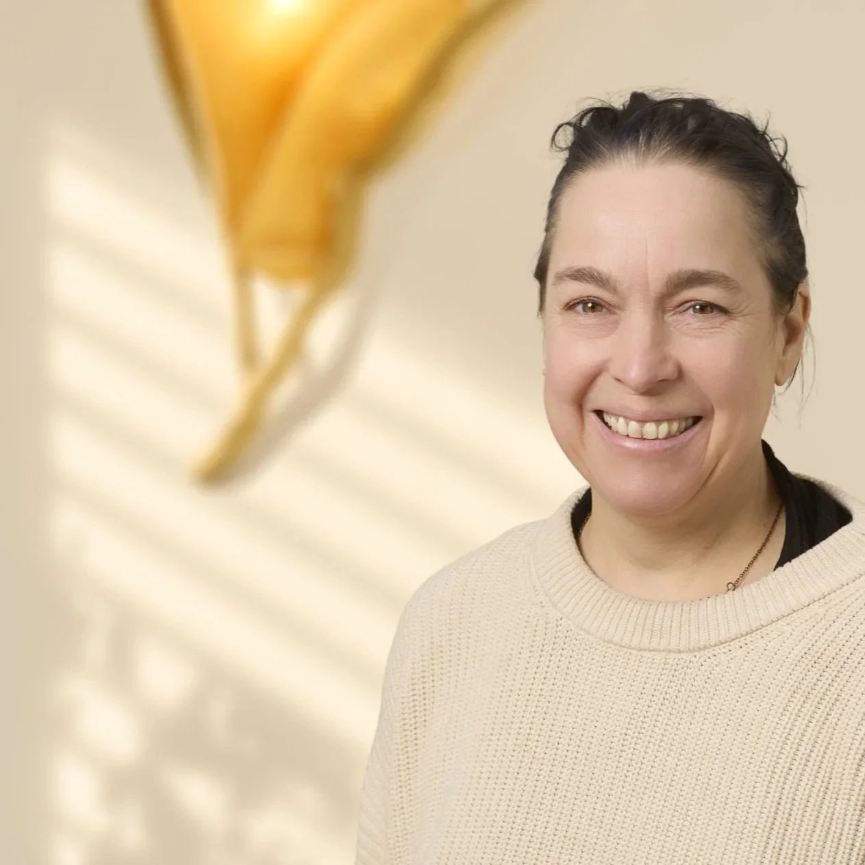 Nahaufnahme einer lachenden Frau vor einer unklaren, hellen Hintergrund.