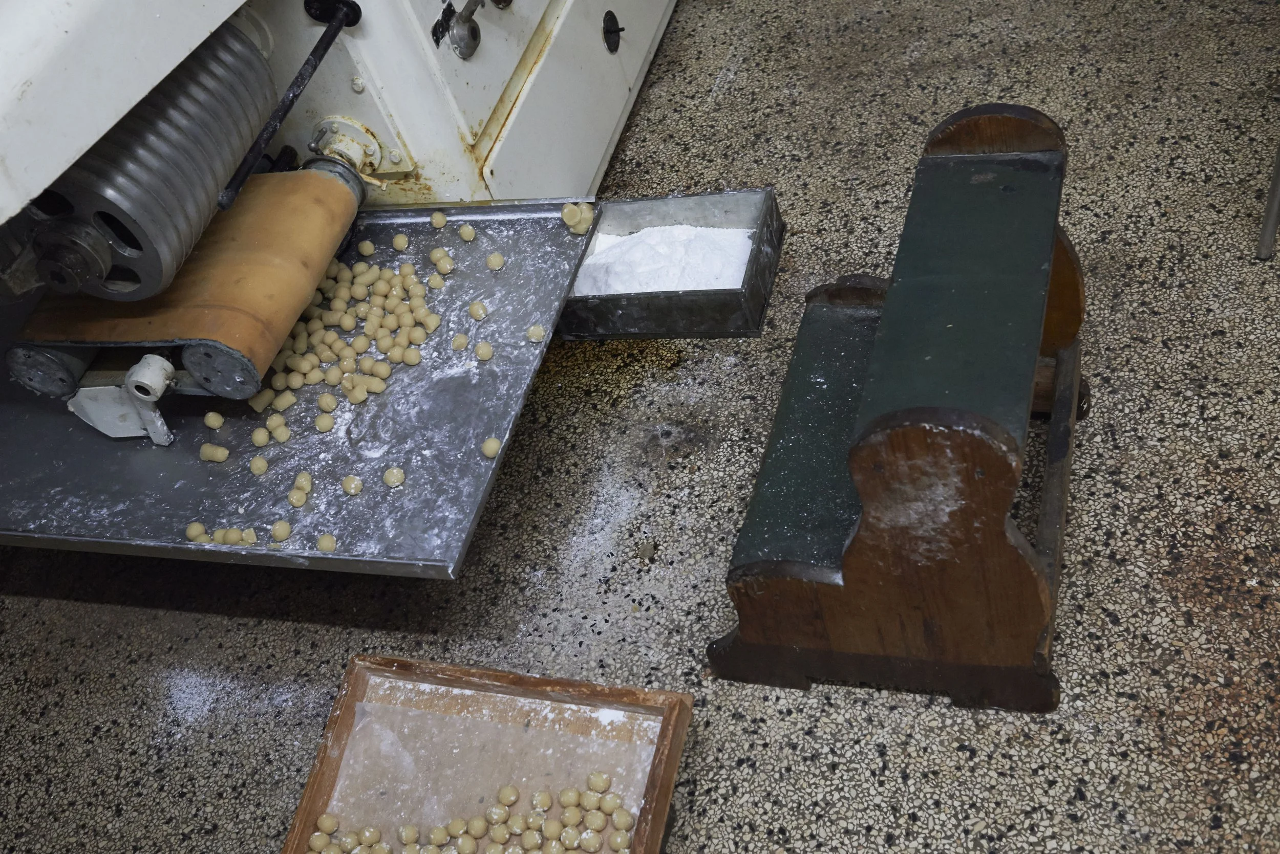 Fertige Marzipankartoffeln vom Fließband. Das Gebetsbänkchen dient als Sitzbank wenn die Kartöffelchen entgegen genommen und aufgefangen werden müssen