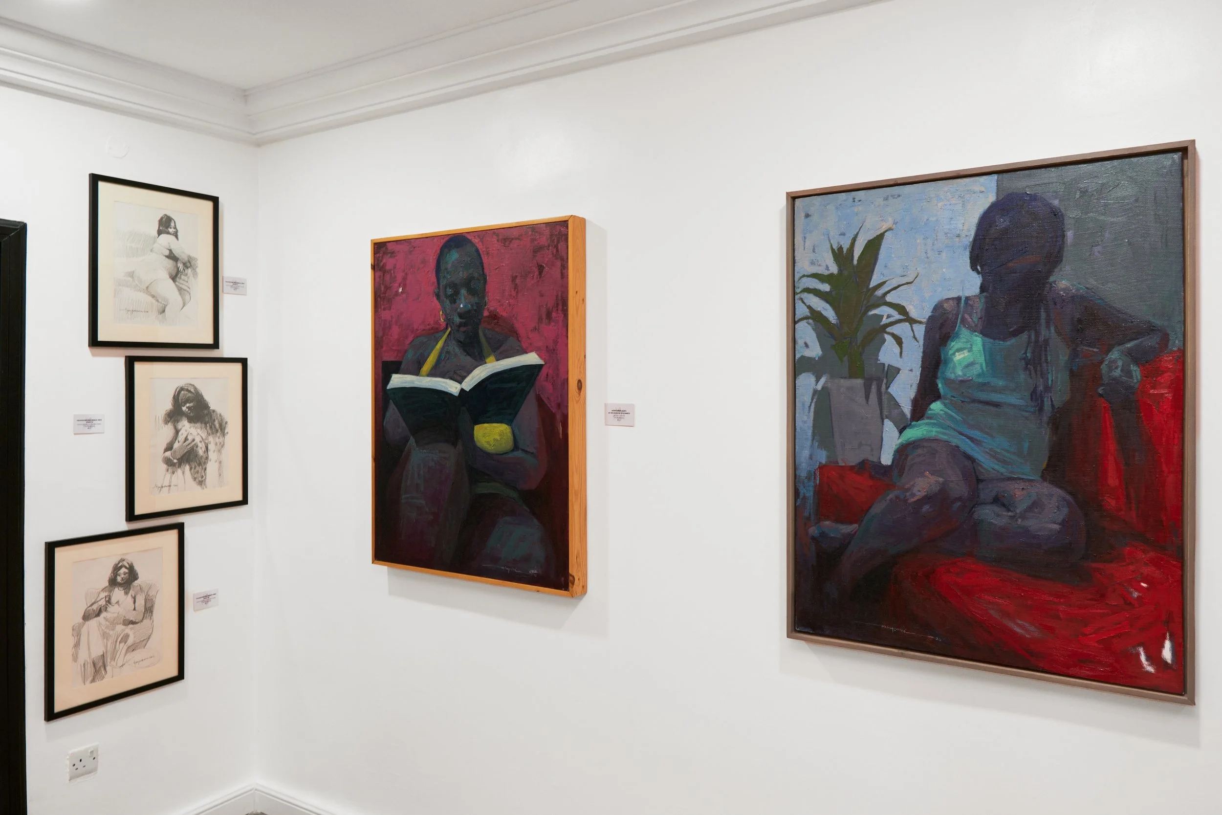 Gallery with various paintings of women, including two sketches and colorful portraits of women sitting, one reading a book and the other lounging near a plant.