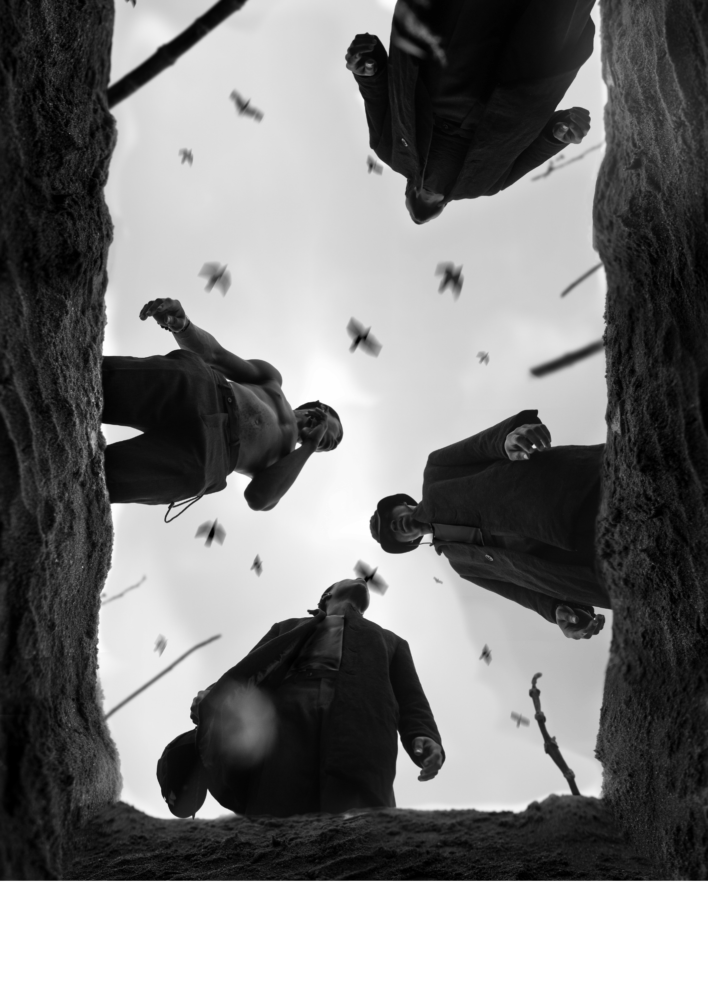 People throwing paper planes into the air from a hole in the ground, viewed from below in black and white.