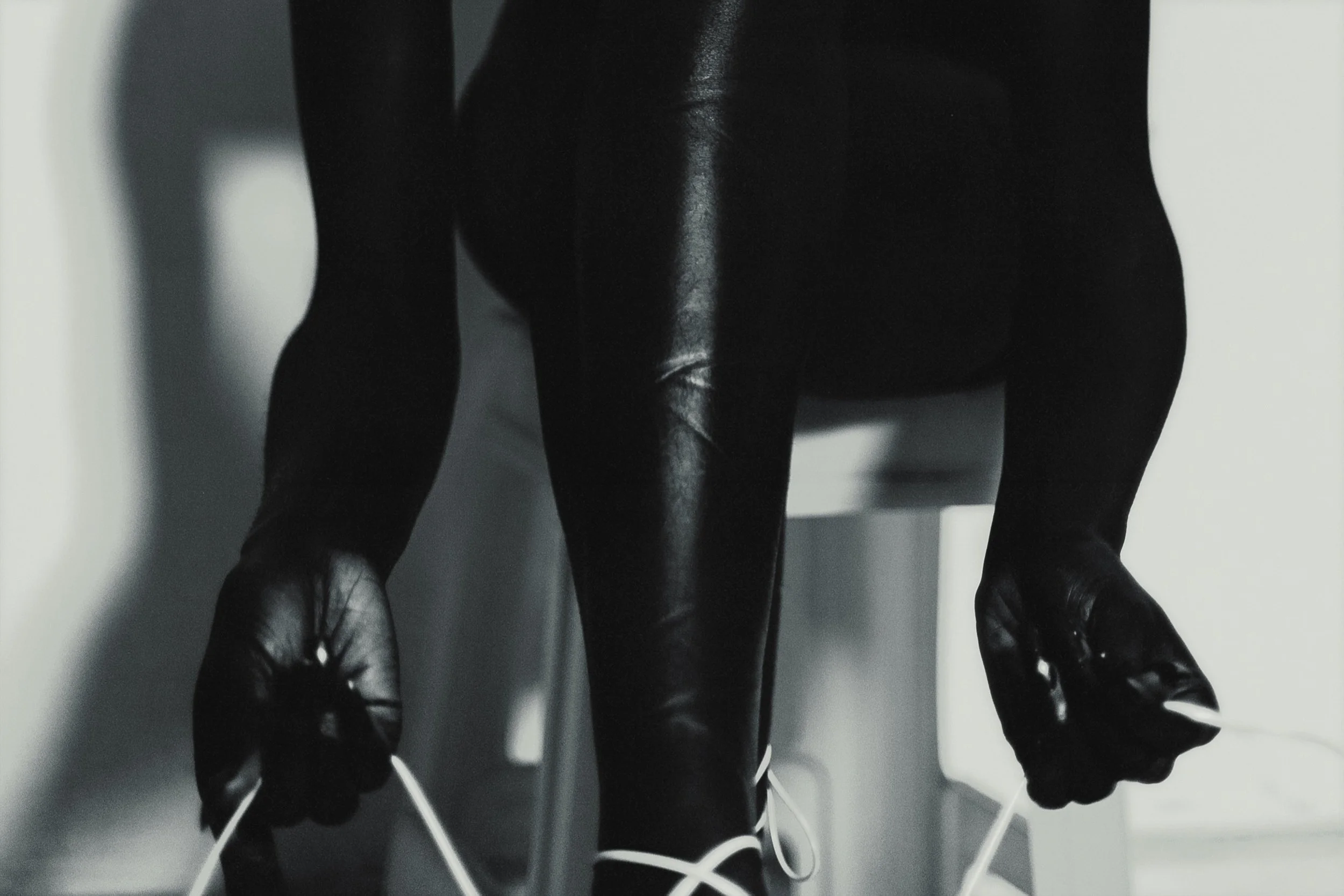 Person in black leather gloves tying shoelaces on white shoes