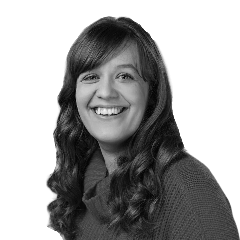 Black and white portrait of a woman with long wavy hair, smiling and looking directly at the camera.