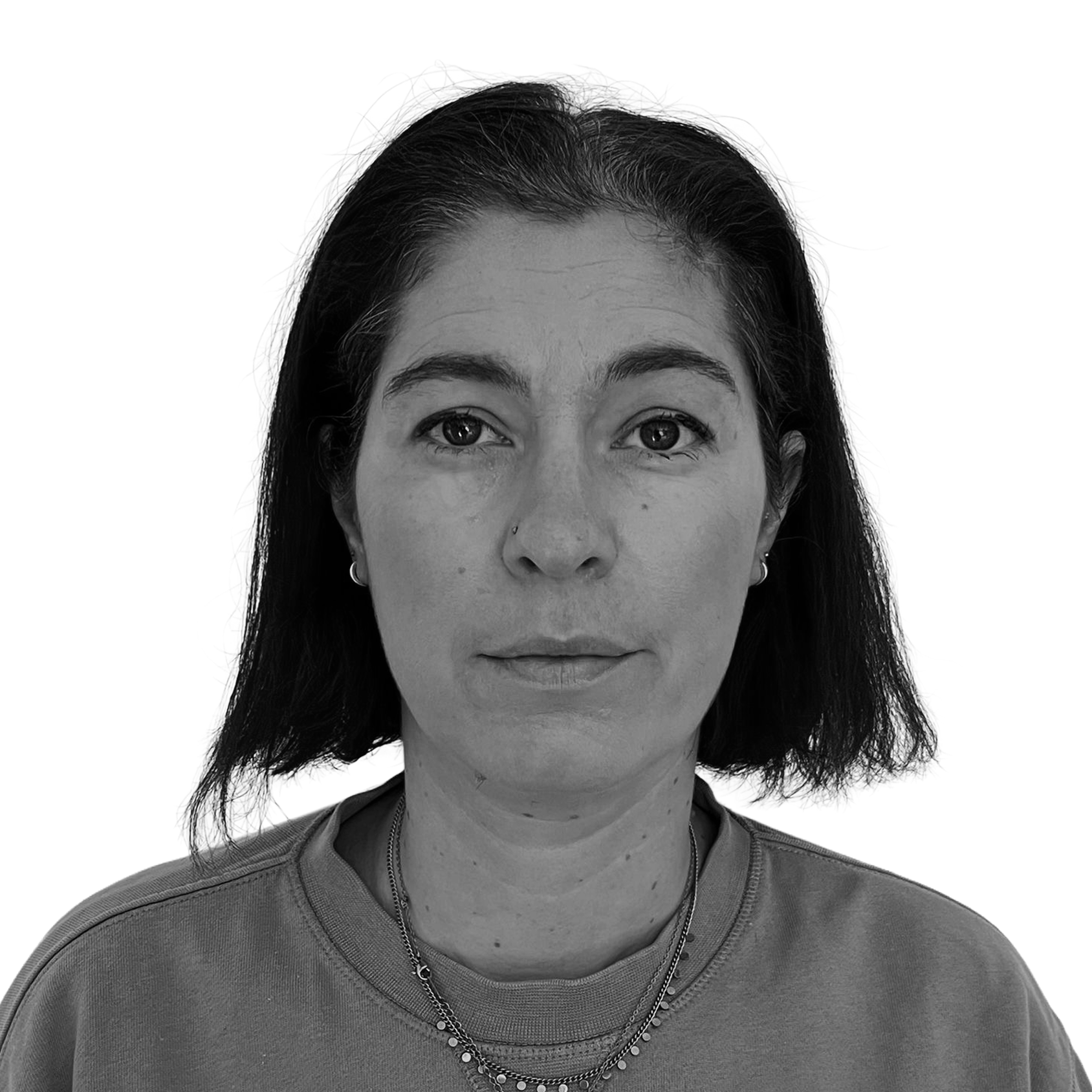 Black and white portrait of a woman with dark hair, wearing a casual shirt and necklaces, looking directly at the camera.
