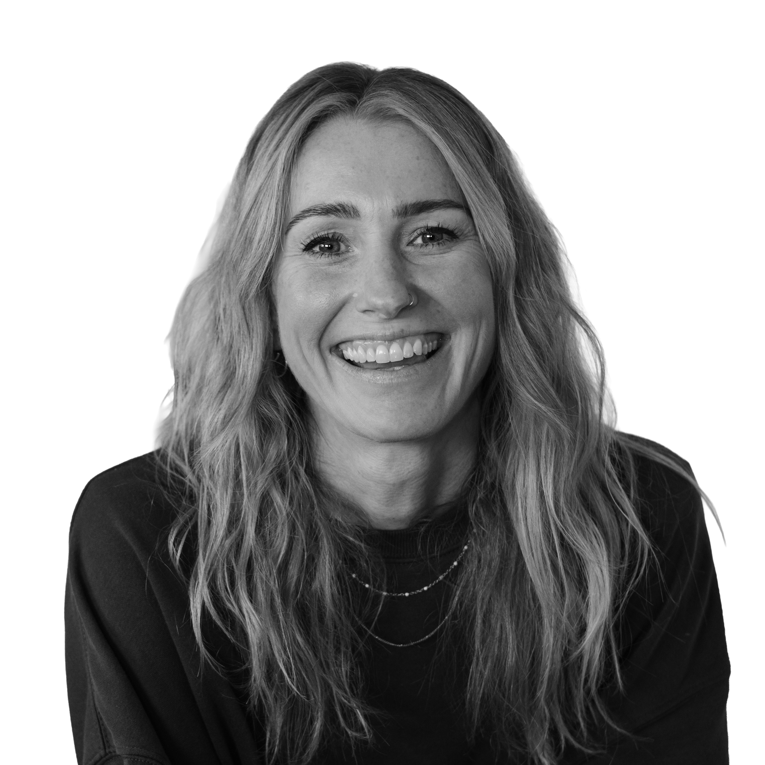 Black and white portrait of a smiling woman with wavy hair, wearing a dark shirt and layered necklaces.