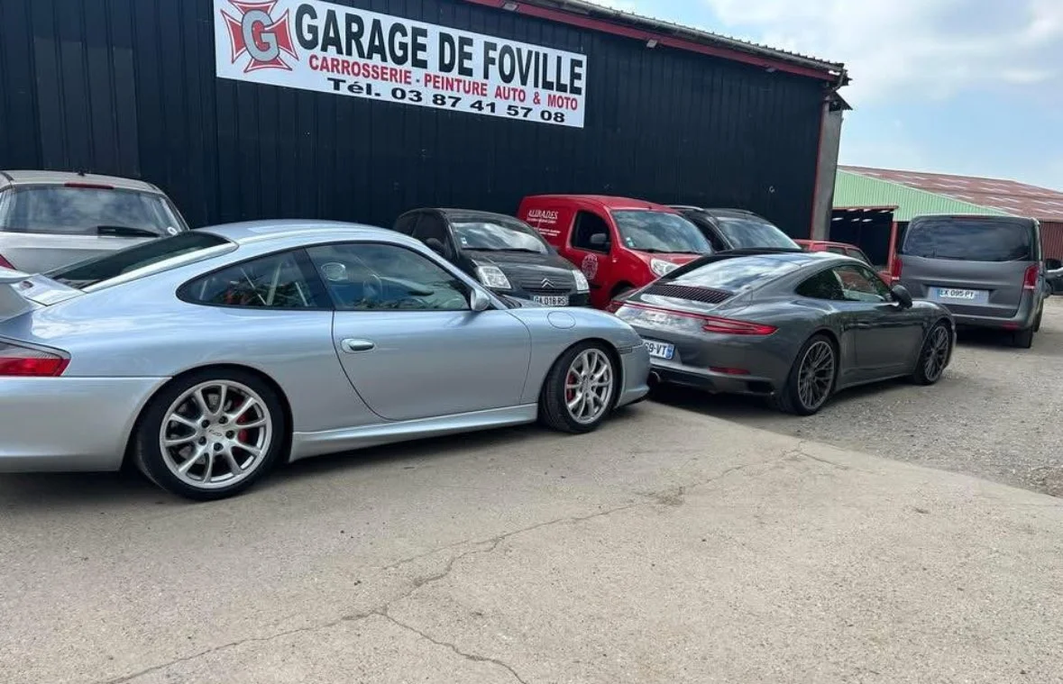 Voitures garées devant un atelier de carrosserie nommé Garage de Foville.