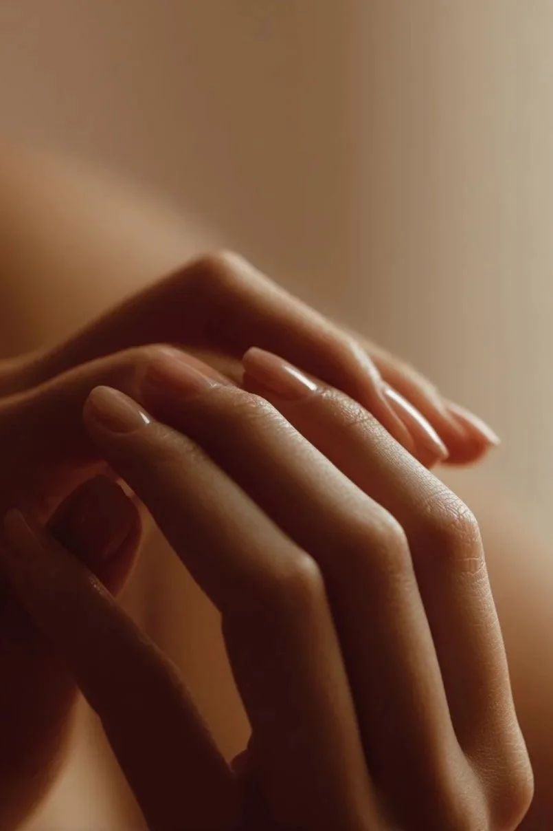 Détail de deux mains qui se touchent délicatement dans une lumière chaude et douce.