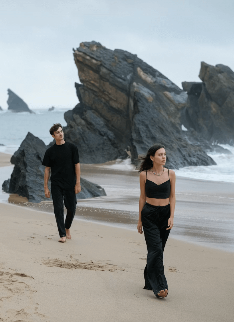pareja en la playa, la mujer va andando delante de el por unos dos metros, parece que han discutido