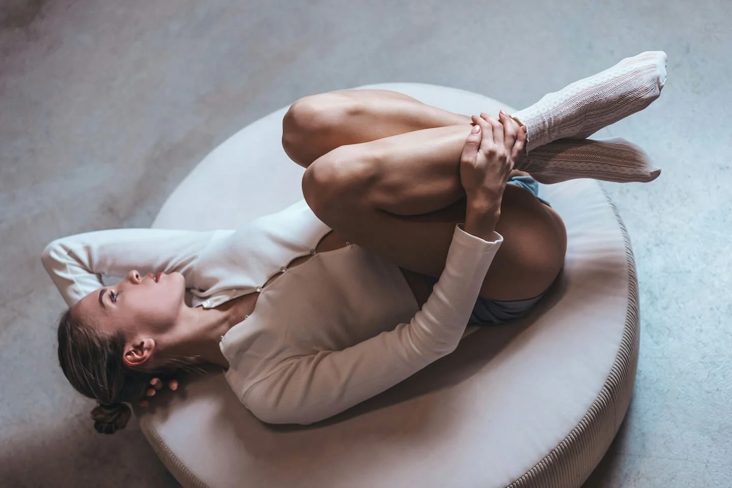 Persona recostada en posición recogida sobre un cojín, simbolizando protección, conexión cuerpo-emoción y la búsqueda de calma y seguridad emocional