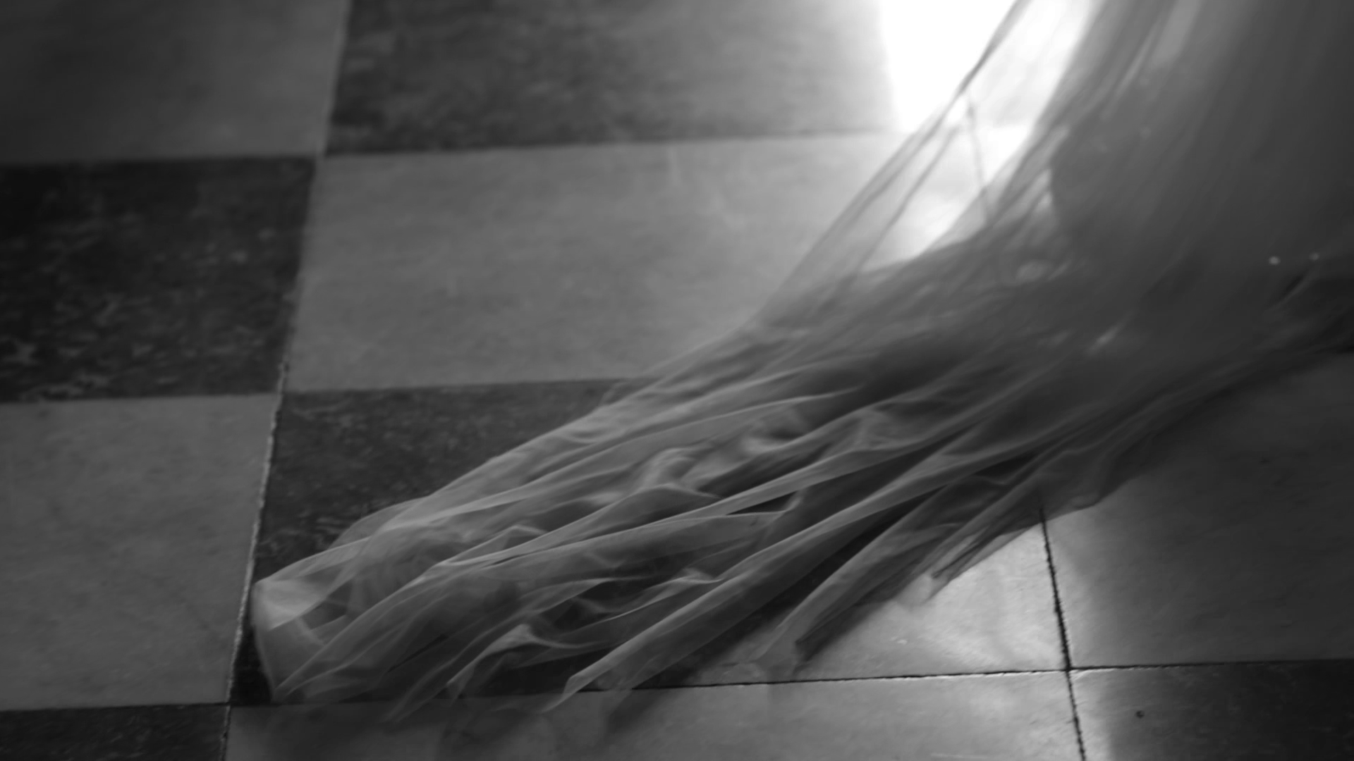 A wedding veil on a checkered tile floor. London wedding videography by Natasha Gray Video.