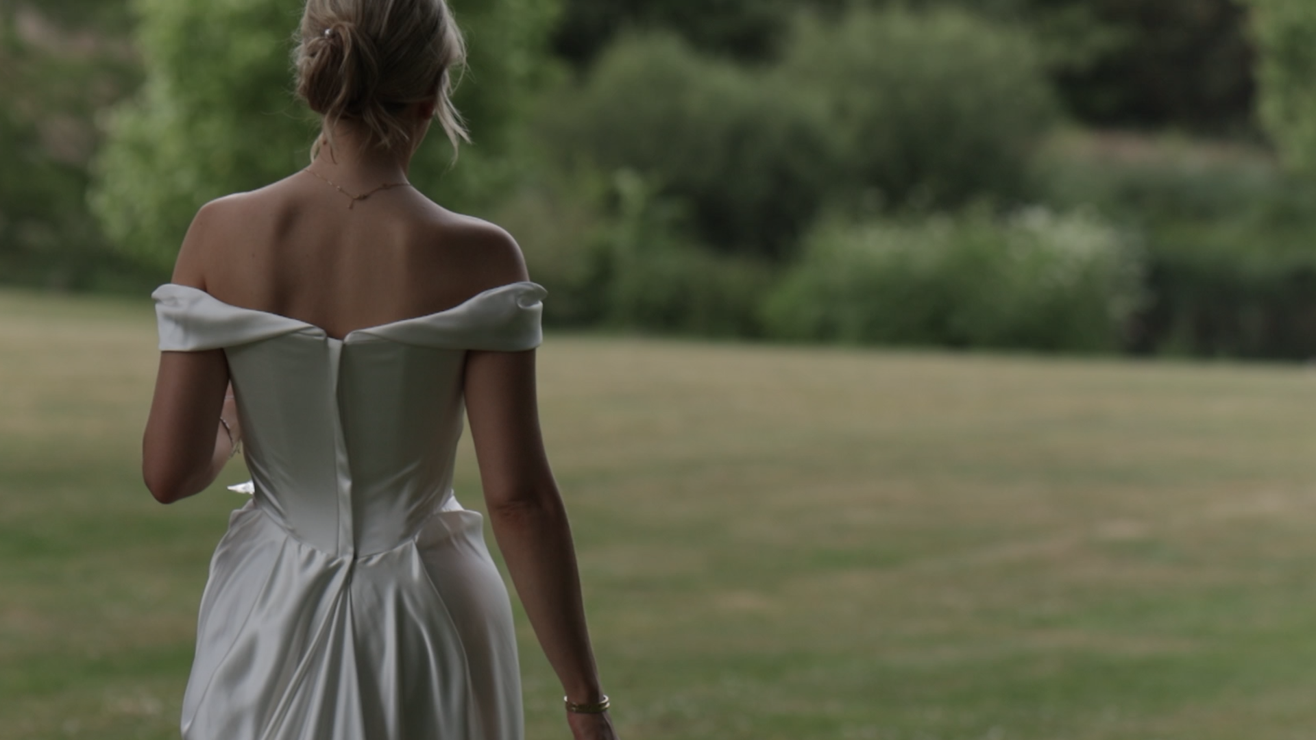 A woman in a Vivienne Westwood wedding dress walking away in the grounds of Syon Park.