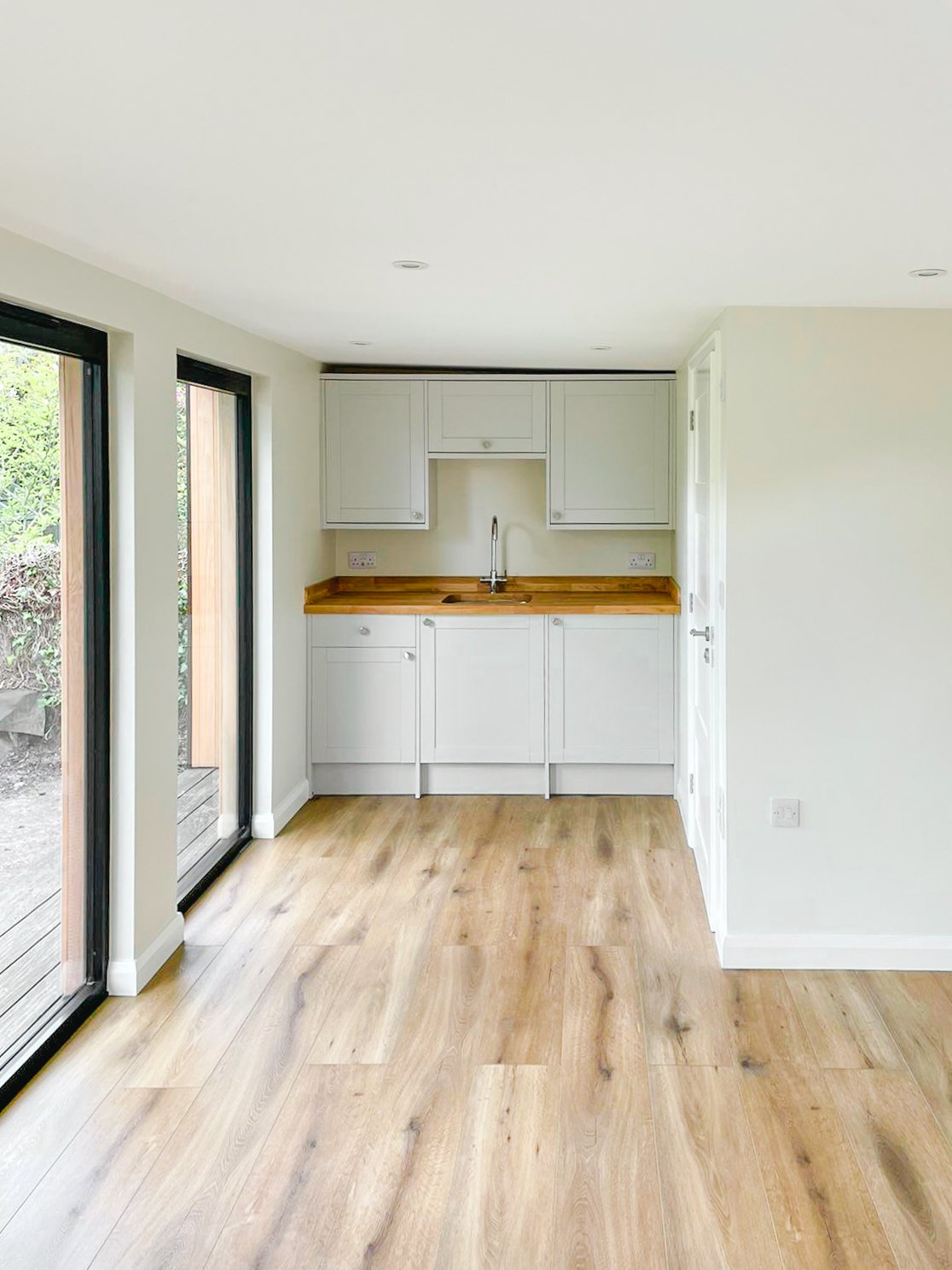 Kitchen area with white cabinets, wooden countertop, and a window to the outside.