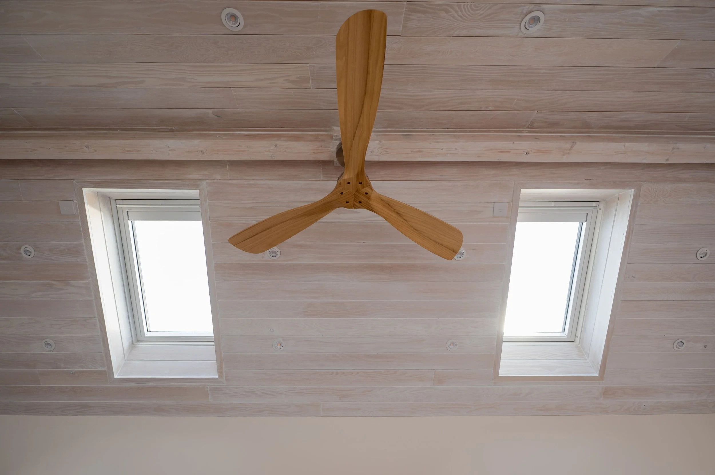 Ceiling with two windows, a wooden ceiling fan, and recessed lighting