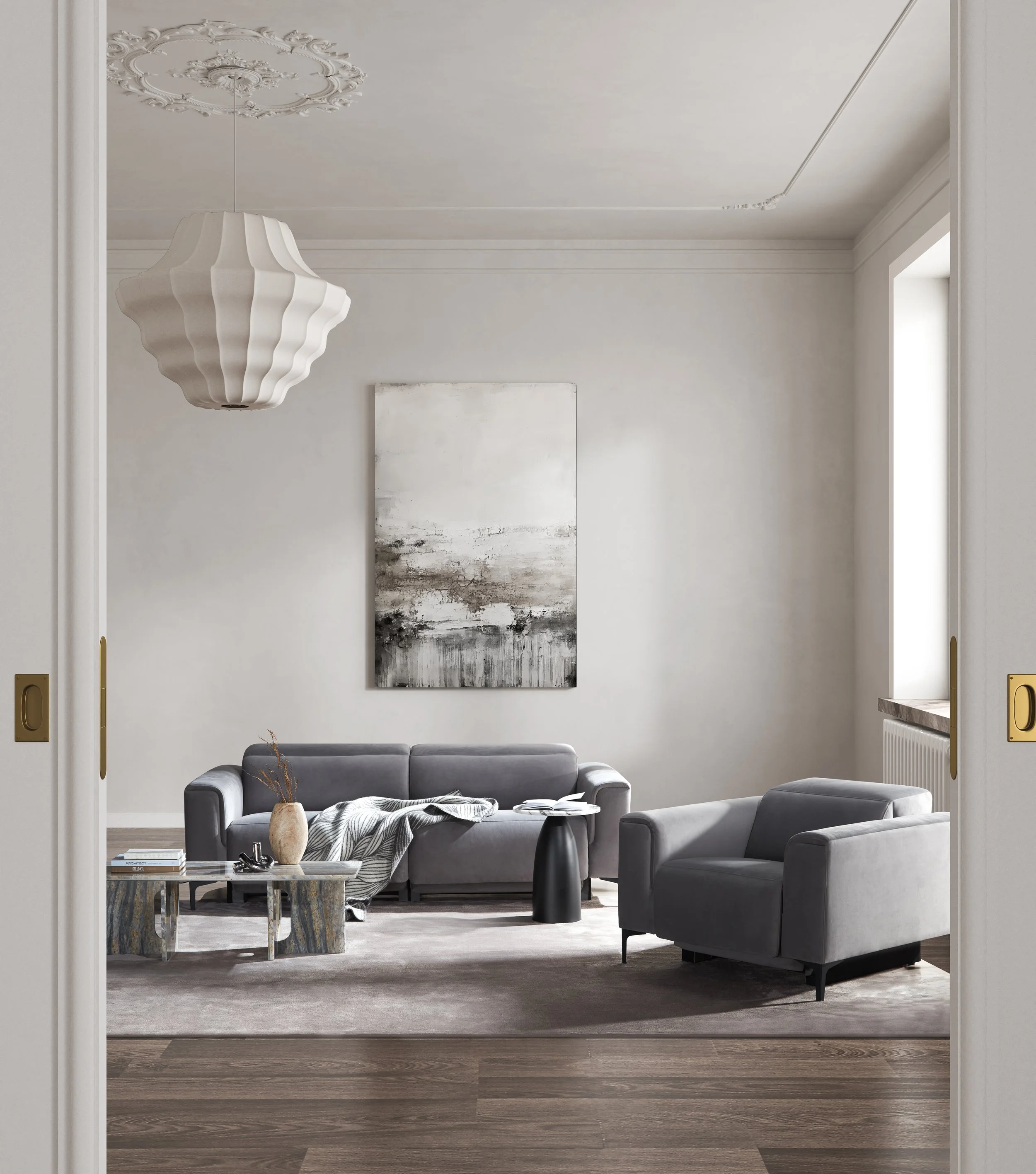 A minimalist living room with grey Nest Space sofas, abstract black-and-white wall art, a side table, and a pendant light with a sculptural shape.