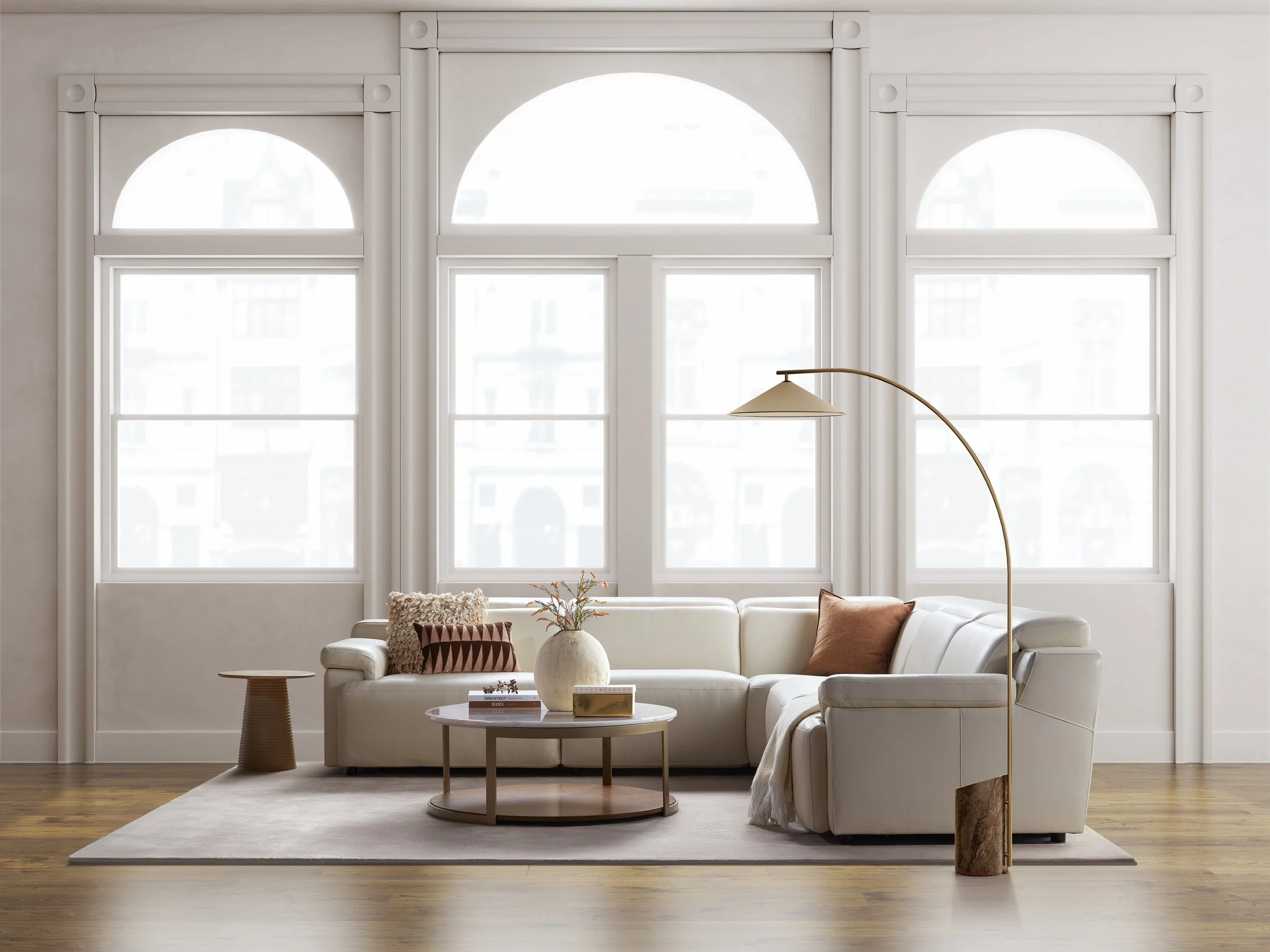 Modern living room with large arched windows, white Nest Space sofa, round coffee table, decorative pillows, potted plants, and a floor lamp on a beige rug.