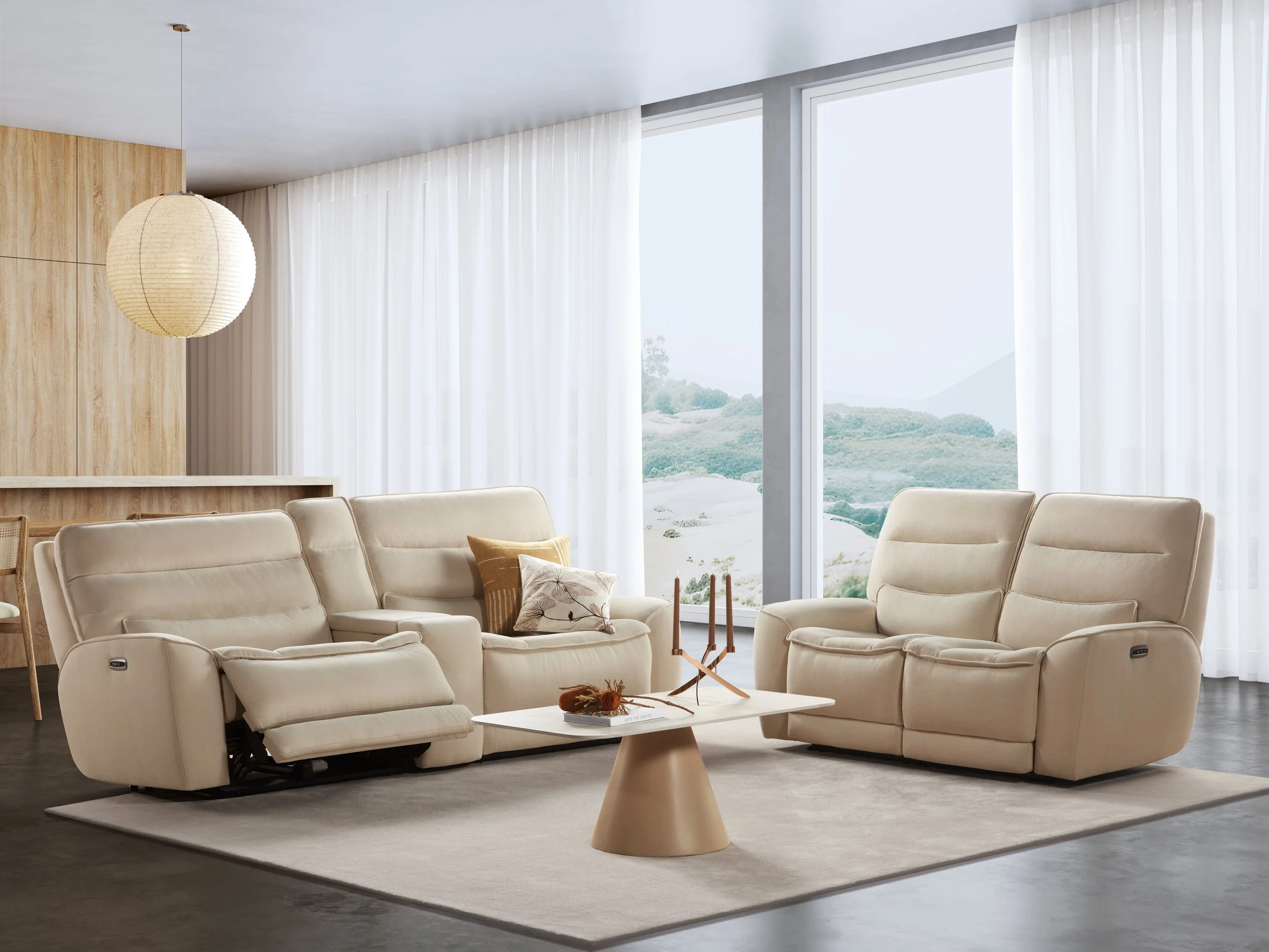 Bright living room with beige Nest Space sectional sofas, a white coffee table, and large windows with white curtains revealing outdoor greenery.