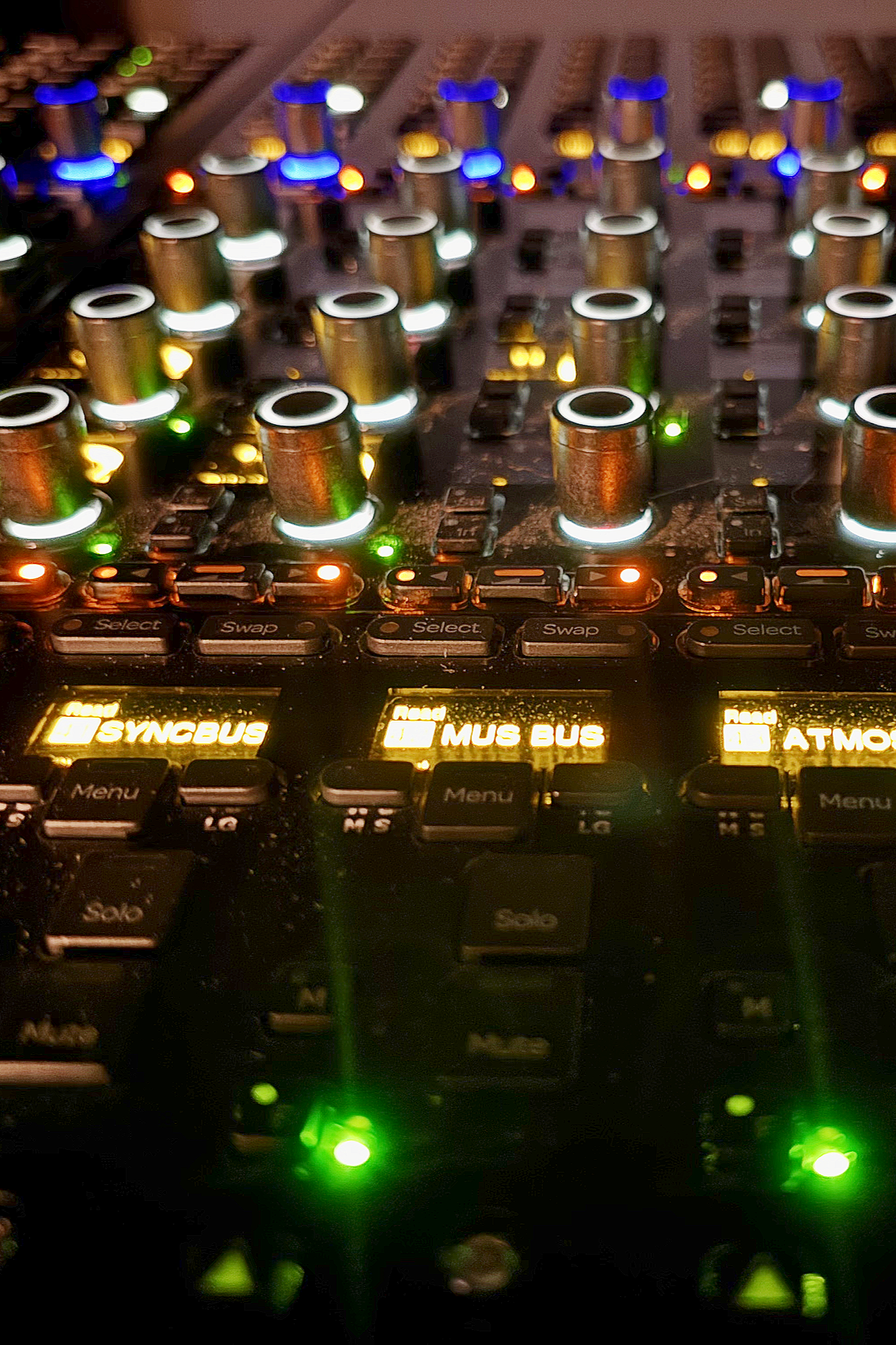 Close-up of a DJ mixing console with illuminated buttons, knobs, and digital displays