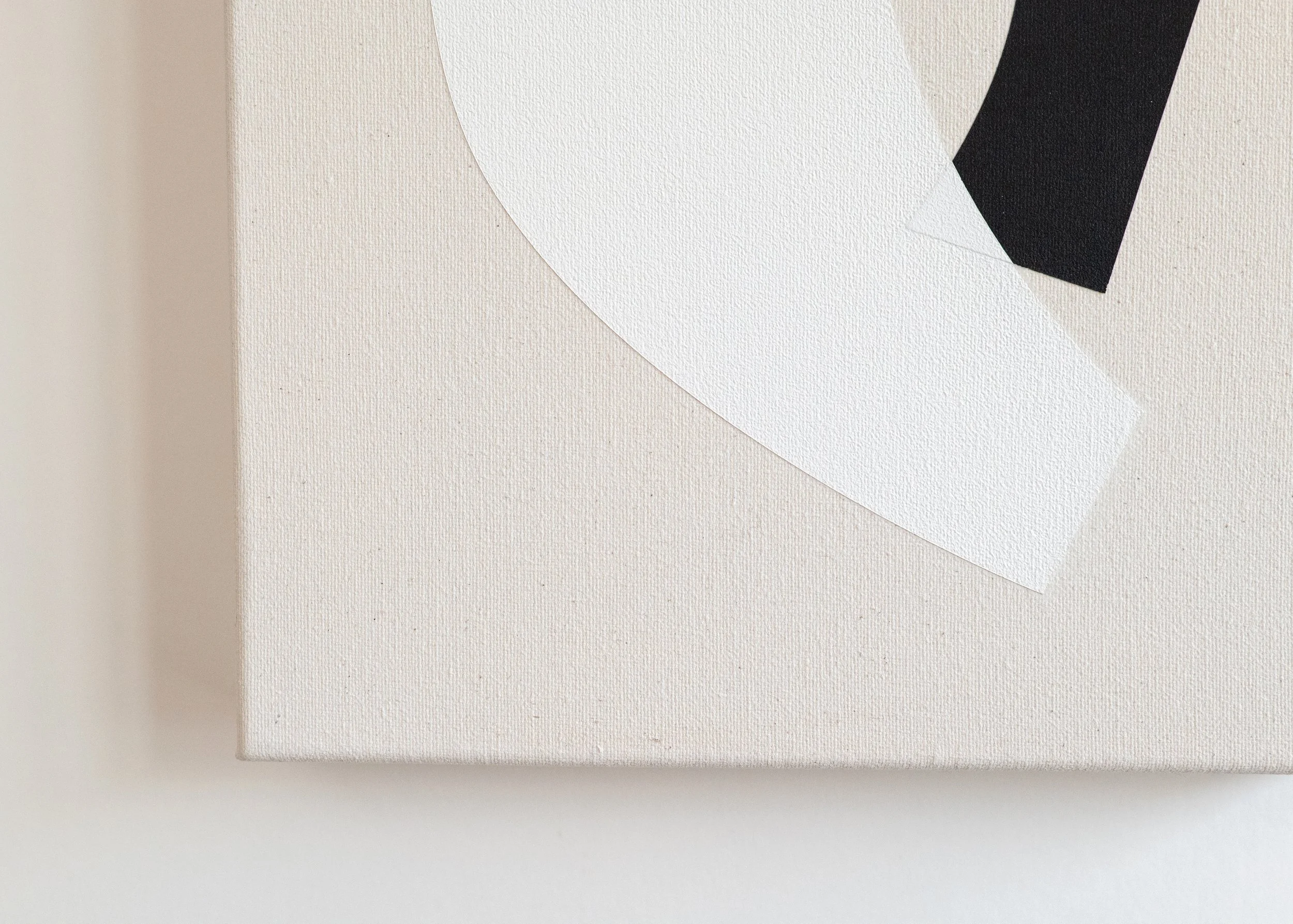 Close-up of a white canvas with overlapping black and white geometric paper cutouts.