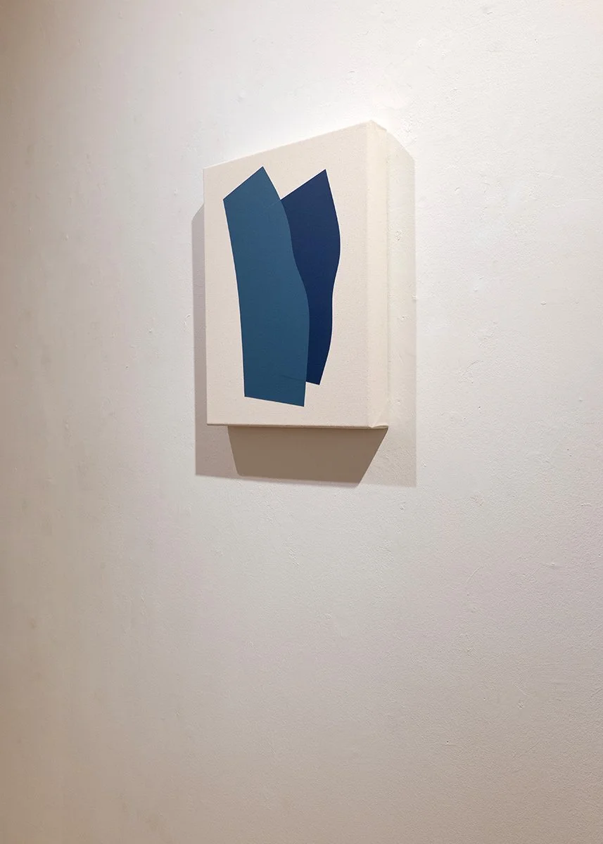Abstract painting with two overlapping blue shapes on a white canvas, hung on a white wall.
