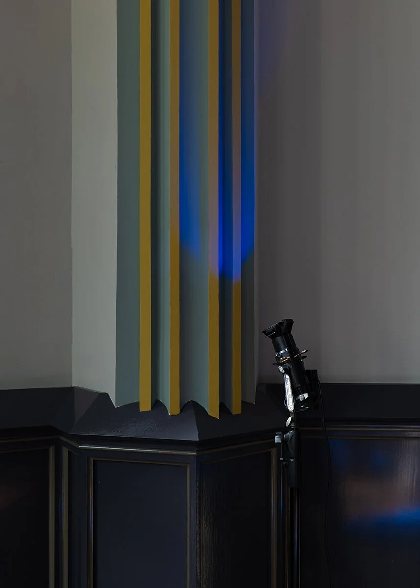 A planetarium with vertical yellow and blue panels and a telescope on a stand pointing towards the ceiling.