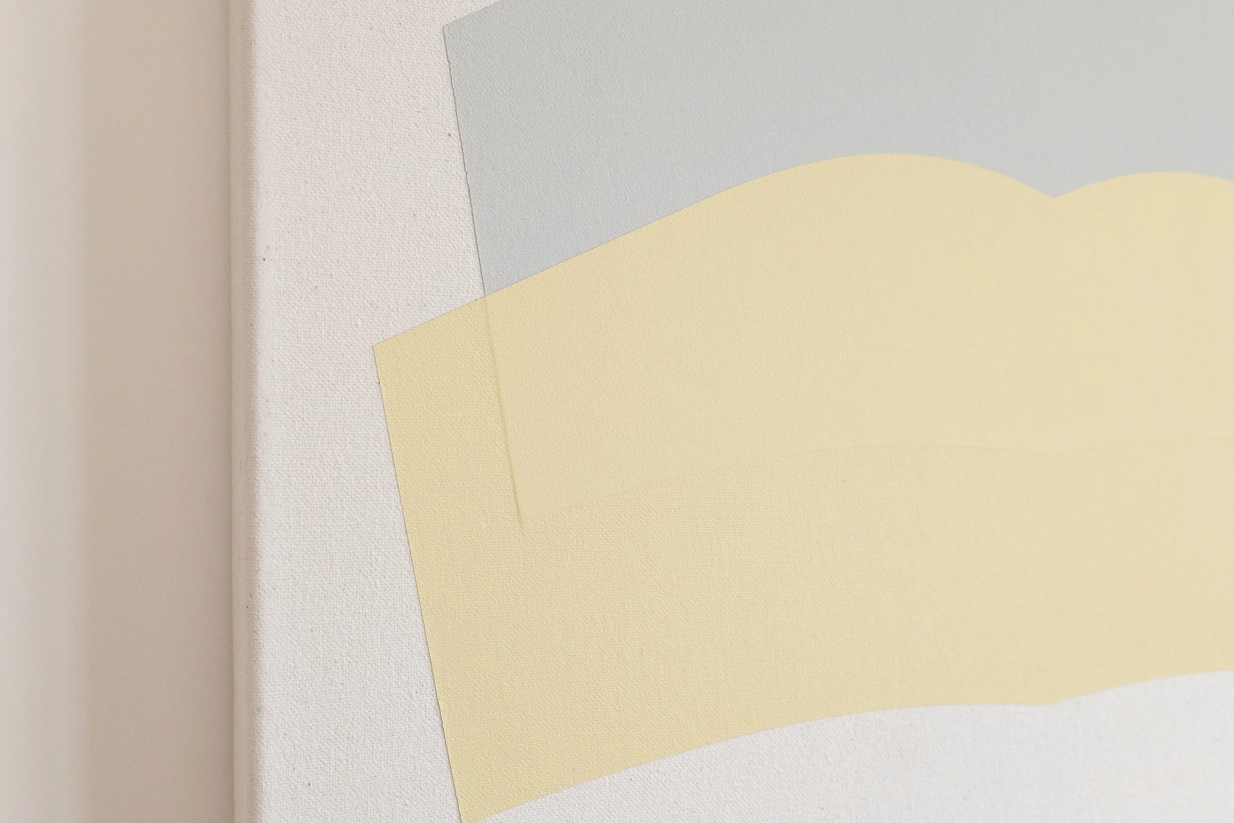 Close-up of textured canvas with overlapping pastel-colored paper in shades of pale yellow, blue, and white.