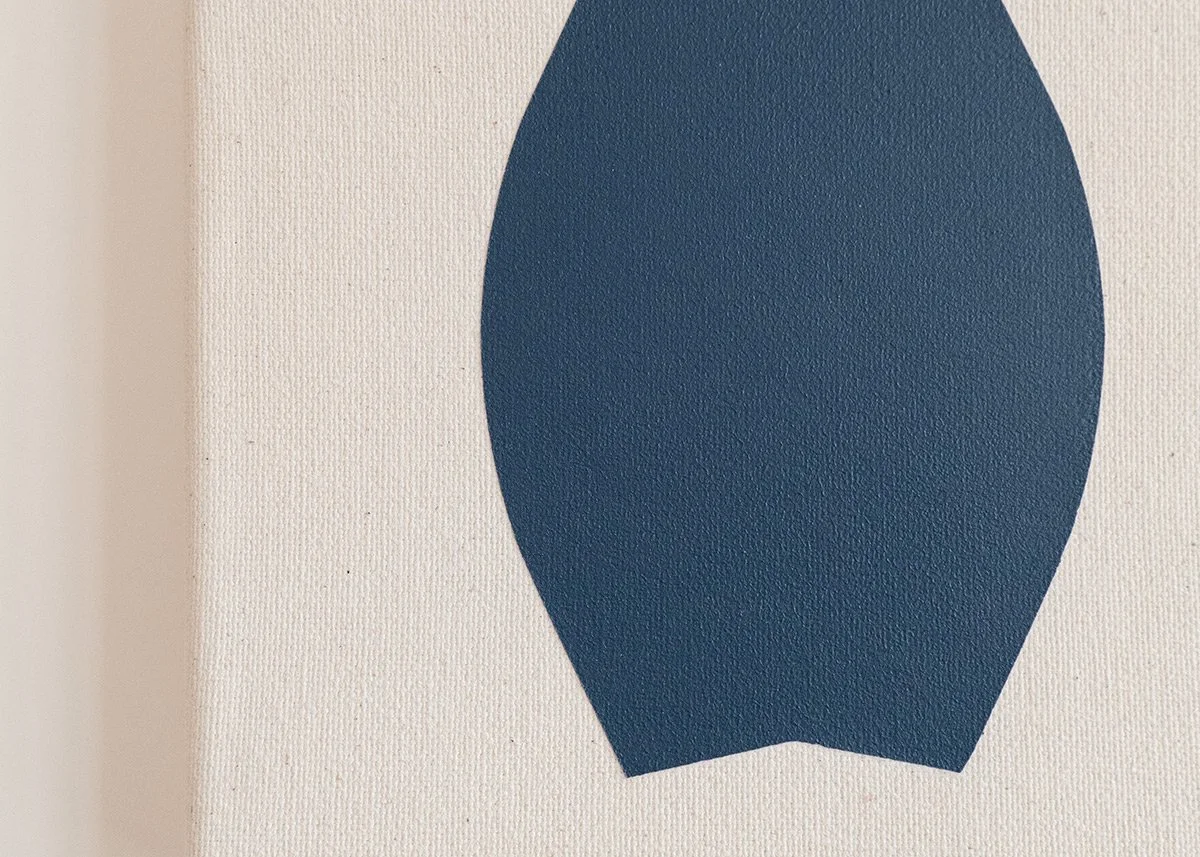 Close-up of a textured white wall with a dark blue geometric shape that looks like a stylized hot air balloon.