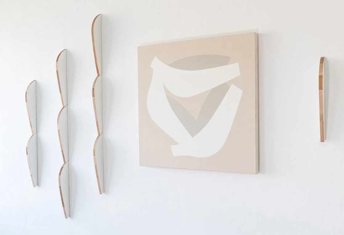 Minimalist wall art with abstract shapes, including a large canvas with beige and white geometric design, and five wavy wooden mounted shelves on a white wall.