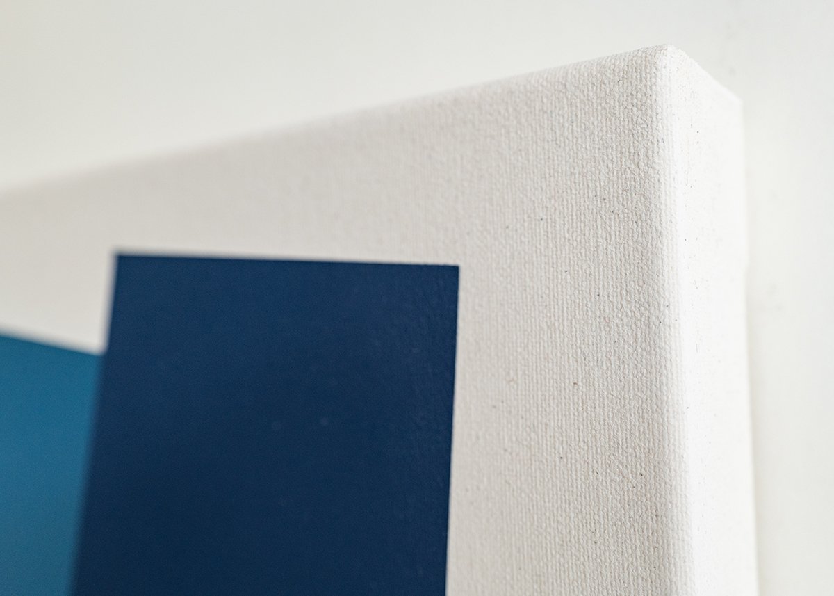Close-up of a canvas with a blue rectangle, showing the textured surface and corner against a light background.