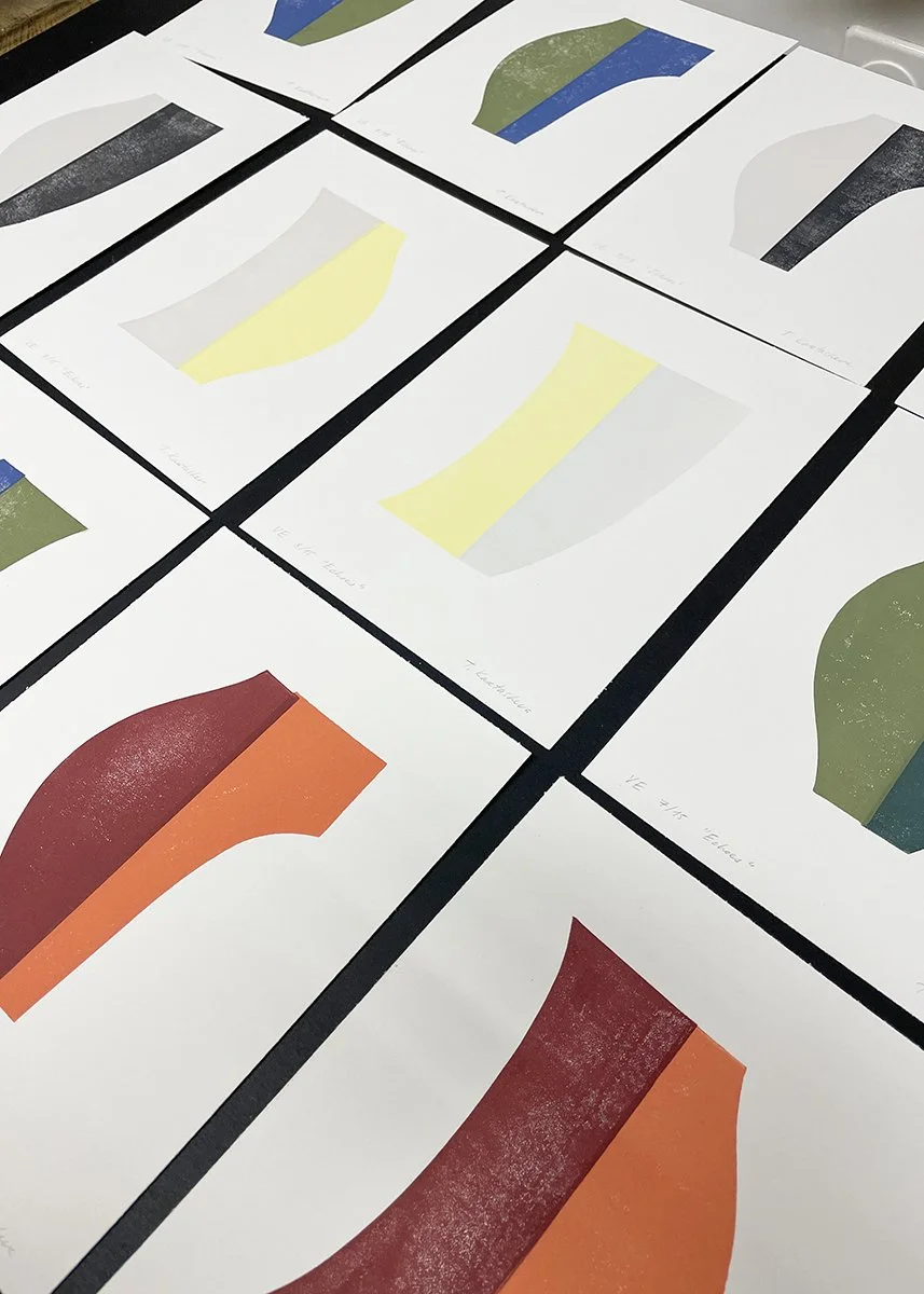Multiple sheets of paper with abstract color-blocked shapes, including yellow, red, orange, green, blue, and gray, spread out on a flat surface.
