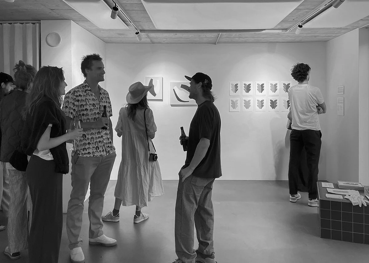 People socializing at an art gallery, observing abstract artworks on the wall.