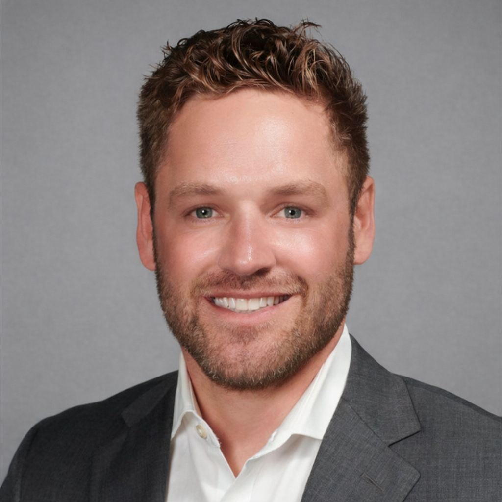 Professional headshot of a smiling man in a dark suit and white shirt against a gray background.